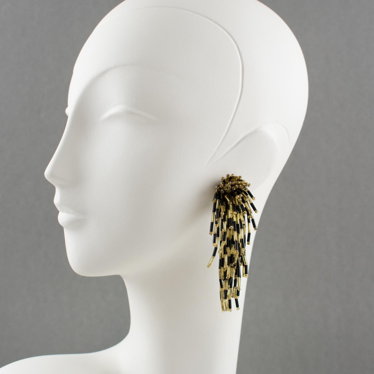 Stunning dangling glass clip-on earrings with a lionfish shape. Oversized shoulder-duster design with cascading waterfall shape built with tiny black and gold glass stick beads. There is no visible maker's mark.
Measurements: 3.57 in long (9.1 cm) x