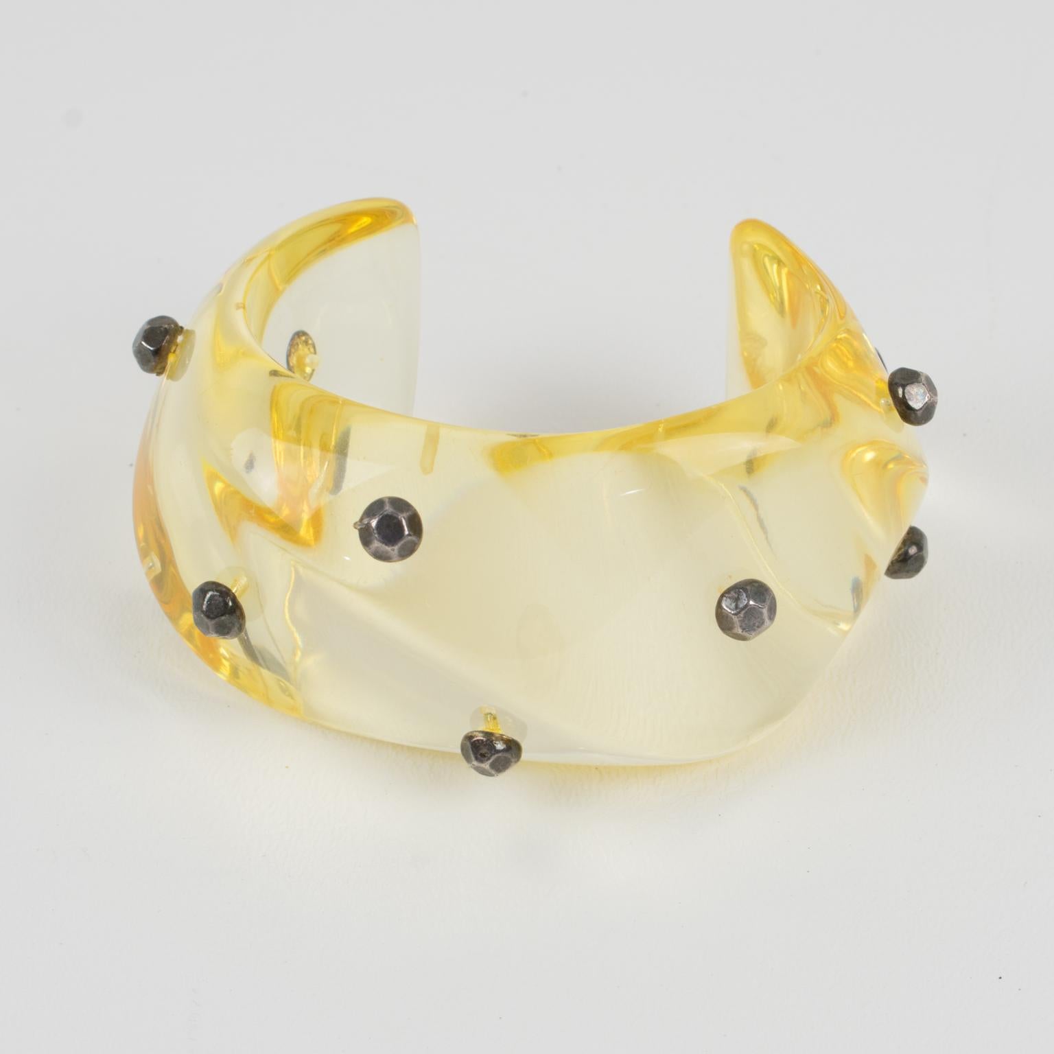 This lovely oversized Lucite cuff bracelet features a bold transparent yellow champagne color Lucite cuff shape with waved carving, topped with faceted silvered metal studs in gunmetal color. There is no visible maker's mark.
Measurements:
Inside