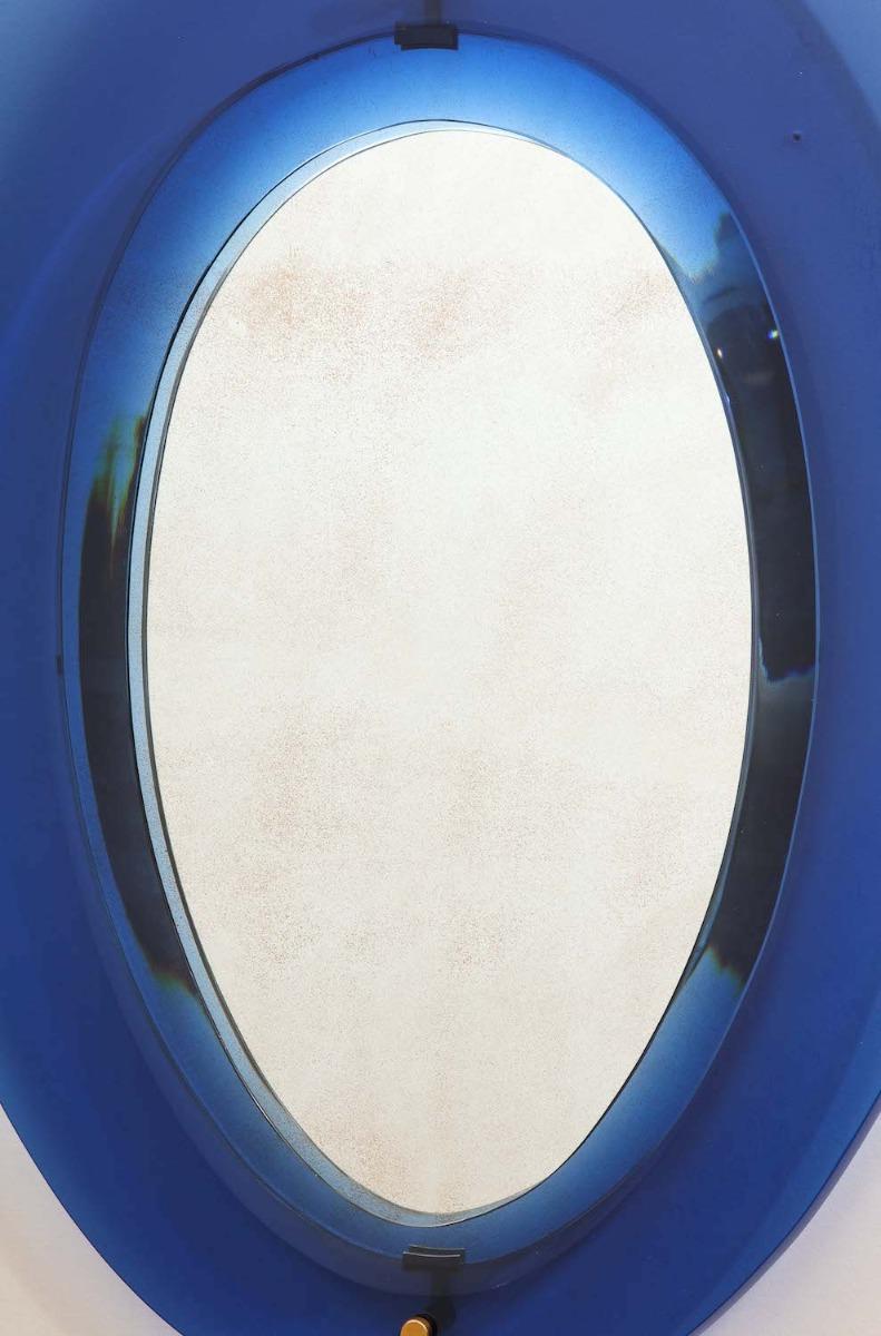 Model #2085. Ovoid shaped mirror with thick blue-glass surround, beveled edges and brass mounts. Published in Fontana Arte 6, makers catalog.