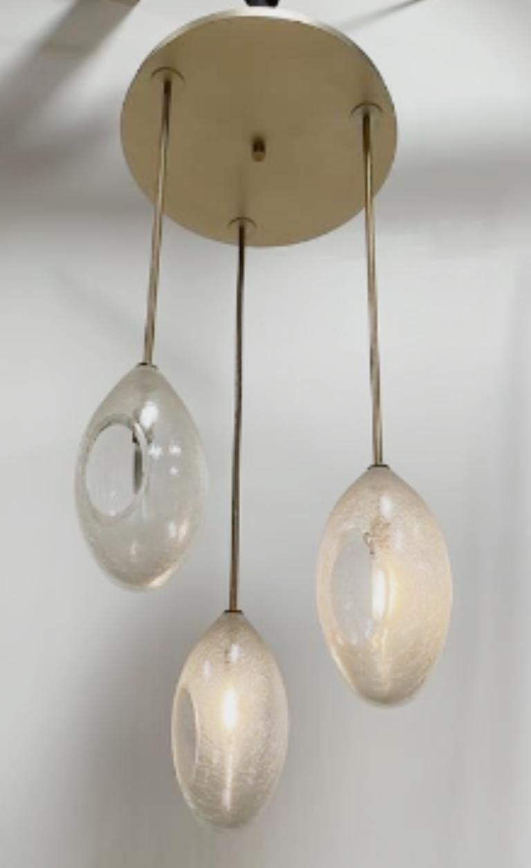 Overscale hand-blown crackle glass 'eggs' sparkle and refract light. A striking solo note or a cascade of shape and light, Ovovo is sensuous with a touch of 60's whimsy.

Flash-cracked and fire-blown glass with polished brass or nickel.

Models in