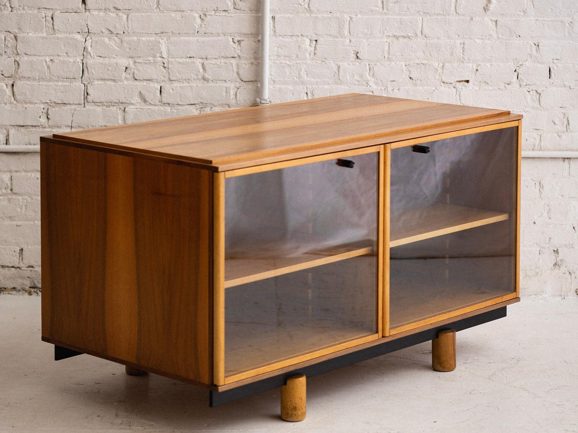 A mid century Italian sideboard cabinet by Gianfranco Frattini for Bernini. Model “806,” this pieces features two glass doors and inner adjustable shelving, blonde wood and black Bernini branded hardware. Designed to be used alone or in tandem with