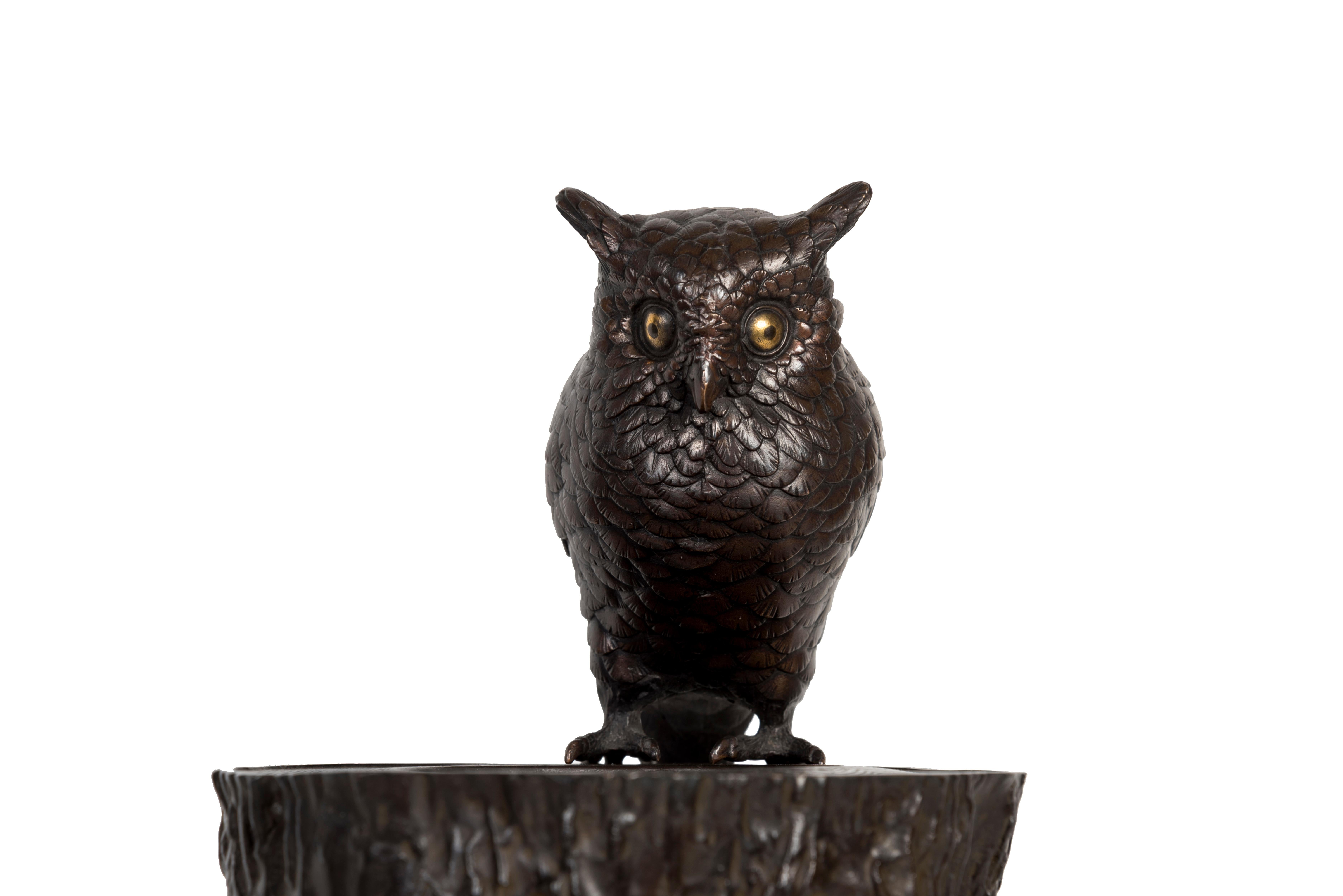 Bronze sculpture representing an owl on a tree stump covered with ivy. The owl, detachable from its base, has shakudo eyes. It is certainly an Ryûkyû scops owl (Otus elegans), present in the south of Japan in Ryûkyû Islands. 
Red fabric glued to
