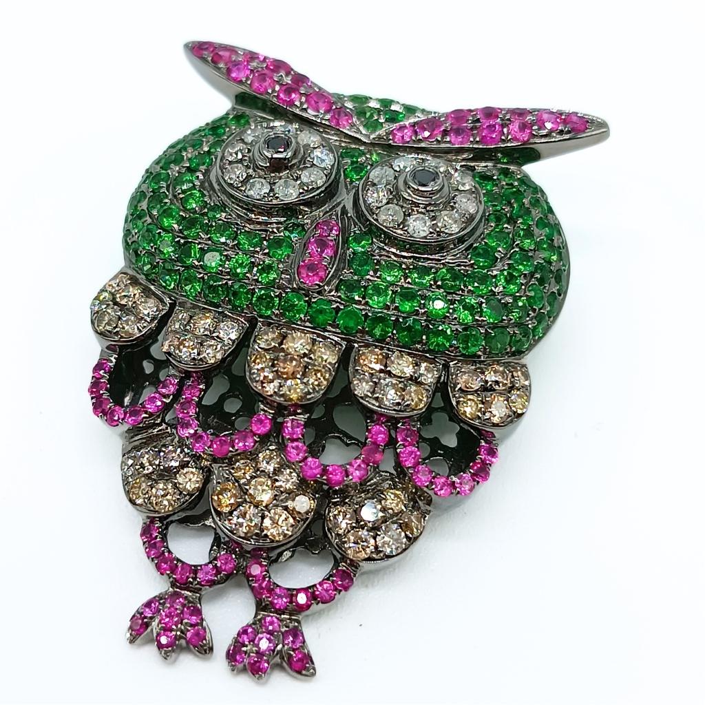 Owl Brooch
18 k White Gold 15,90gr
70 brilliant-cut Diamonds 1,44k 
2 black brilliant-cut Diamonds 0,05k 
116 round-cut Tsavorites 2,69k
77 round-cut Rubies 1,35k 