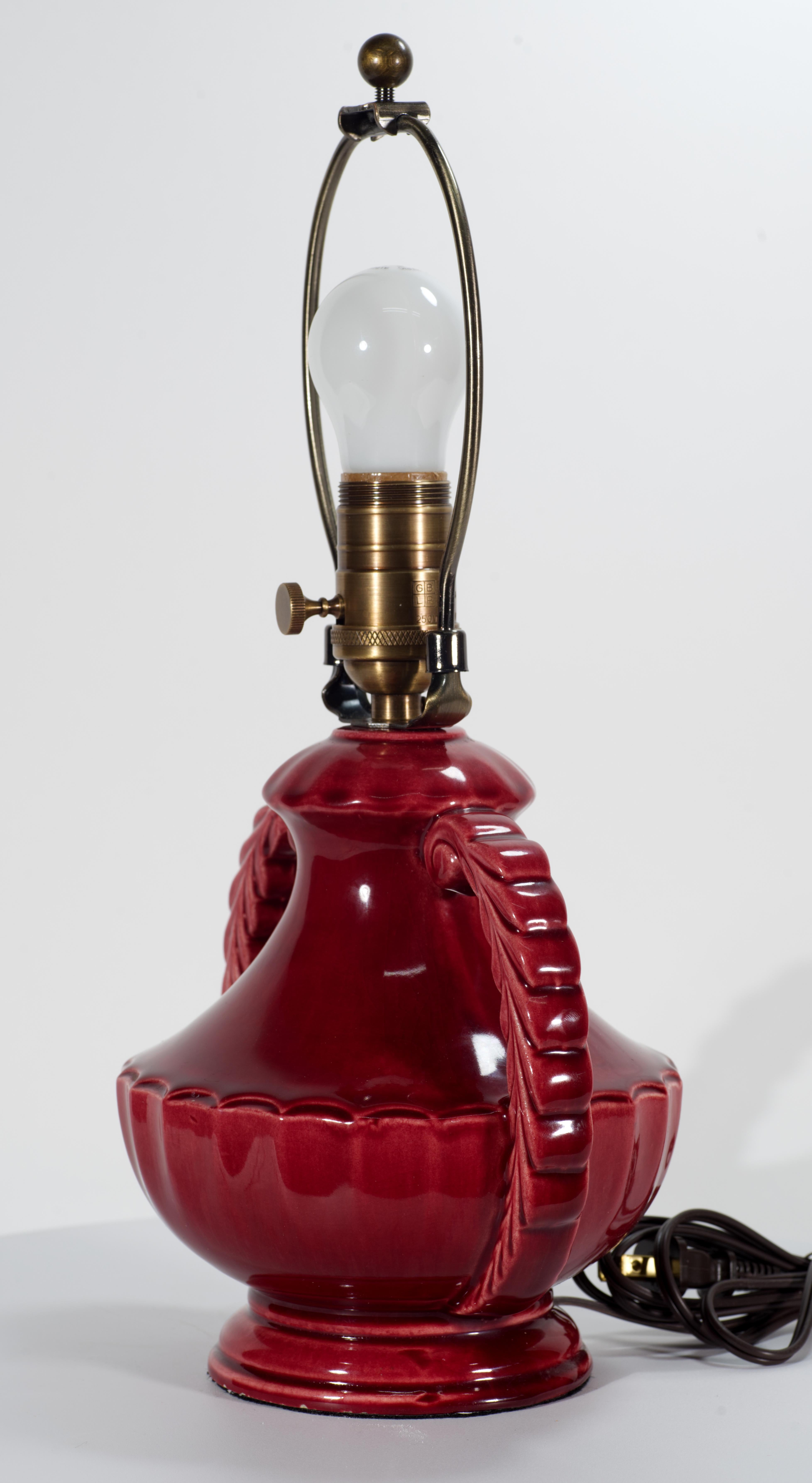  Lámpara escultórica vintage con esmalte rojo burdeos oxblood que presenta un elaborado cuerpo en forma de urna de cerámica de estilo Art Déco con dos asas ornamentales. El rico y colorido esmalte monocromático con ligero efecto craquelado