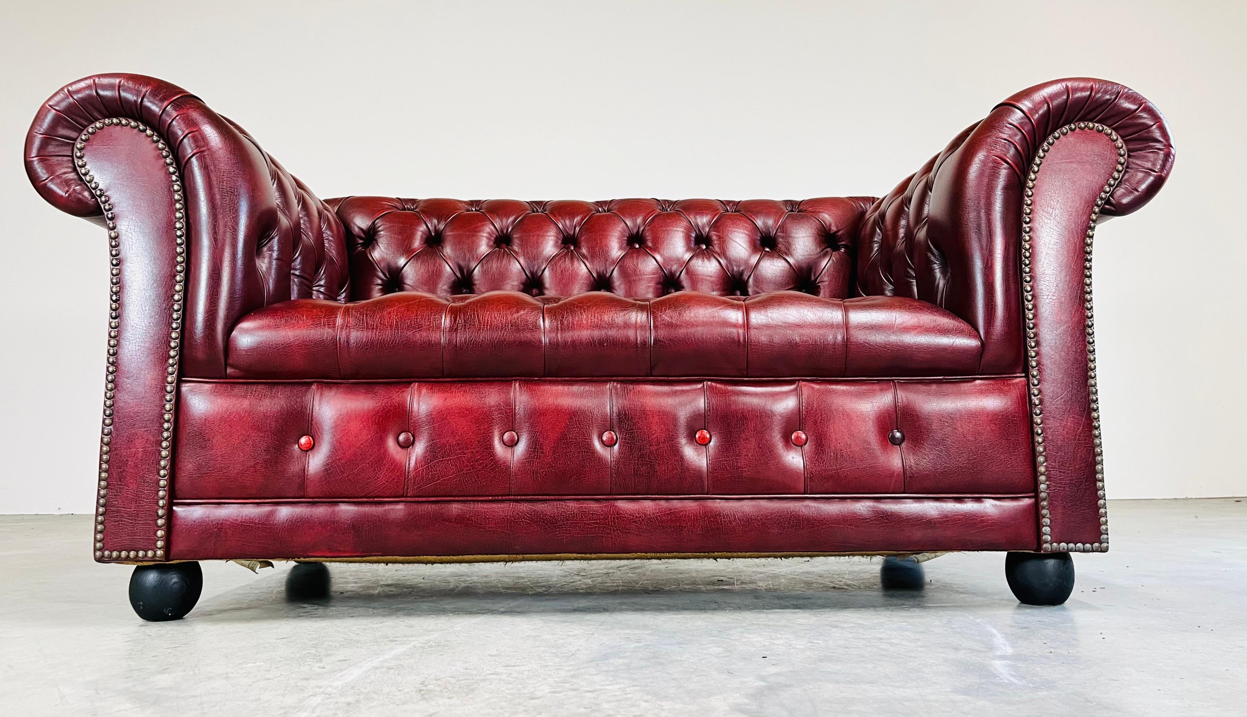 A stunning Chesterfield 2-seater sofa in oxblood leather having turned onyx mahogany cannonball feet by Action Furniture Ltd. Of Great Britain where the finest Chesterfield sofas are made. 
Circa 1970. 
In outstanding condition having no cuts, holes