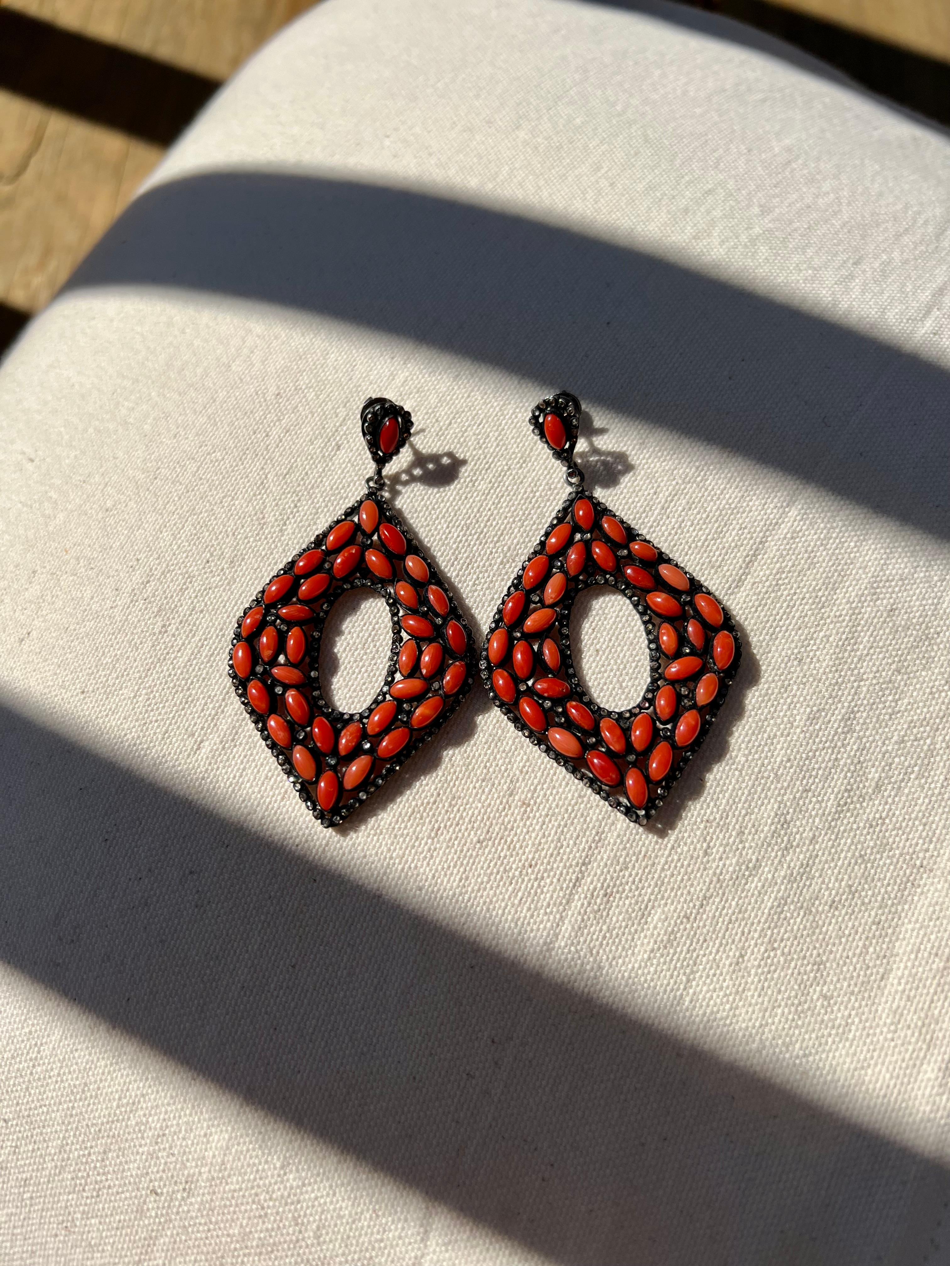 One pair of oxidized sterling silver dangle earrings set with seventy (70) 6x3mm oval oxblood coral stones and two hundred ninety-six rose cut diamonds.  The earrings measure 70mm long and are 39mm wide complete with friction posts and backs.  