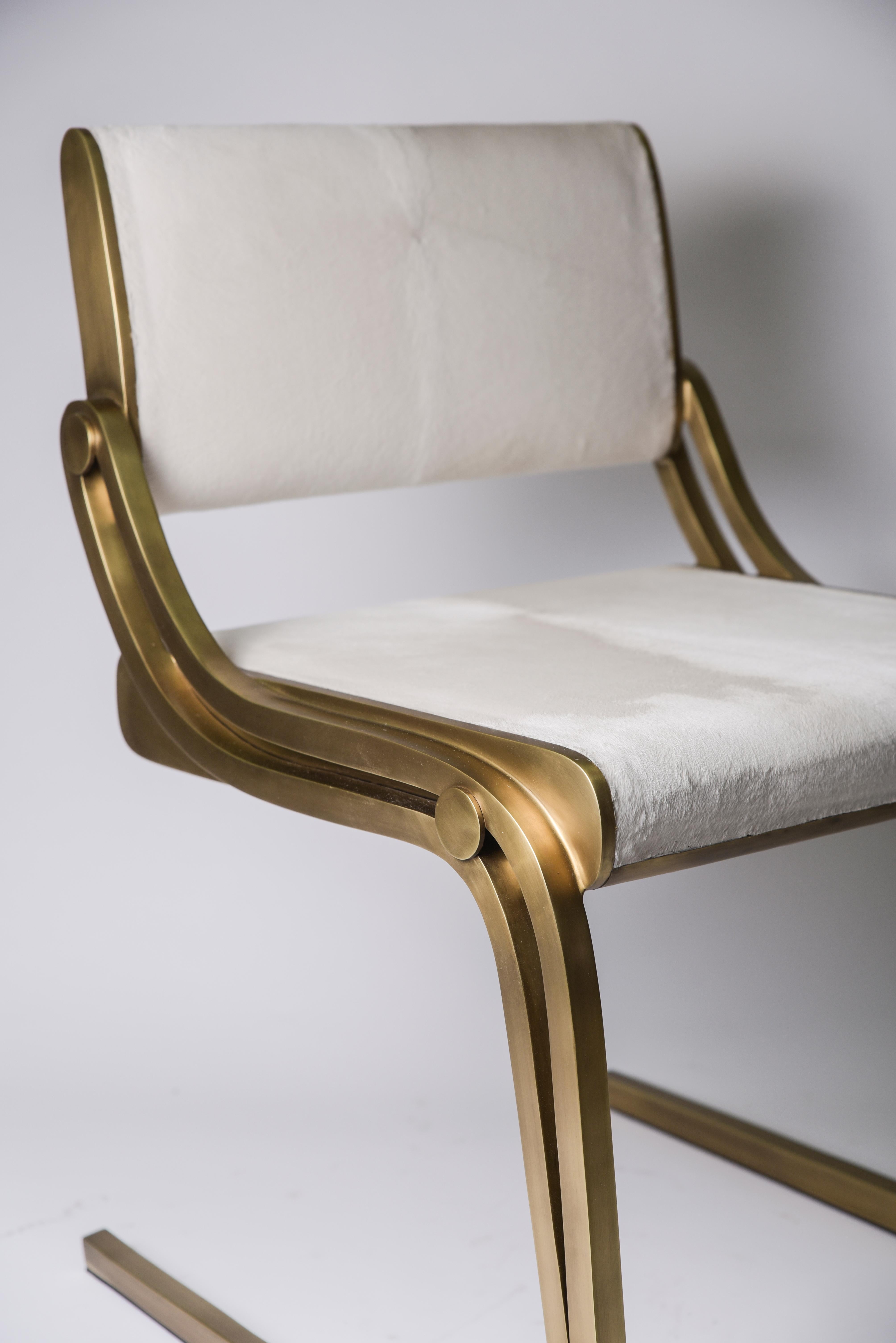 La chaise Oxford de R&Y Augousti est une pièce sophistiquée qui offre du confort, tout en conservant son esthétique élégante et luxueuse. Cette pièce est tapissée d'un cuir de veau crème lustré et doux, avec un cadre en laiton bronze-patiné.