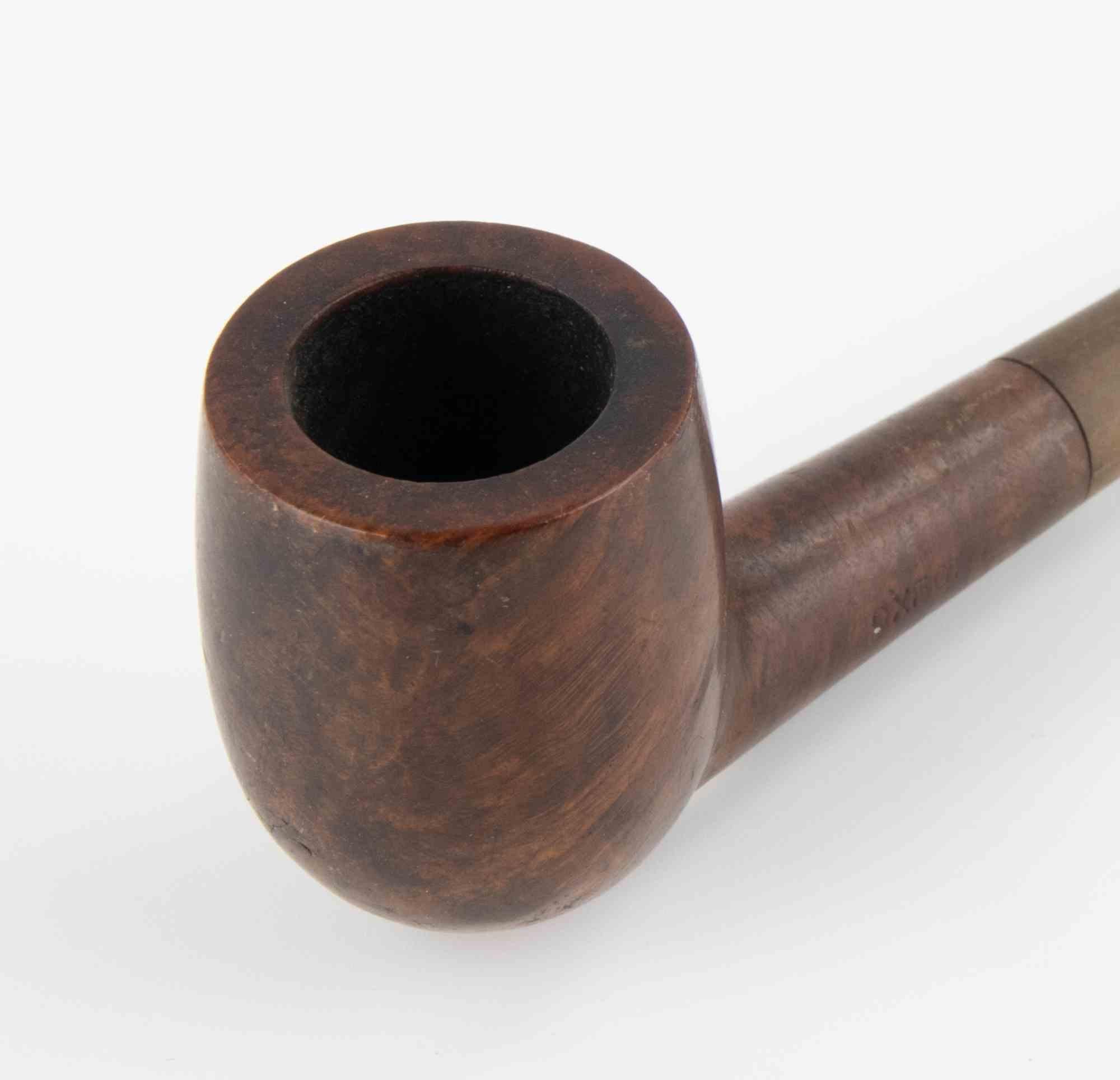Pipe à fumer vintage de style churchwarden d'Oxford, remarquable par son tuyau allongé qui offre une expérience de fumage fraîche et douce. Le bol est fabriqué en bois de bruyère avec une patine chaude de noyer, contrastant élégamment avec la tige