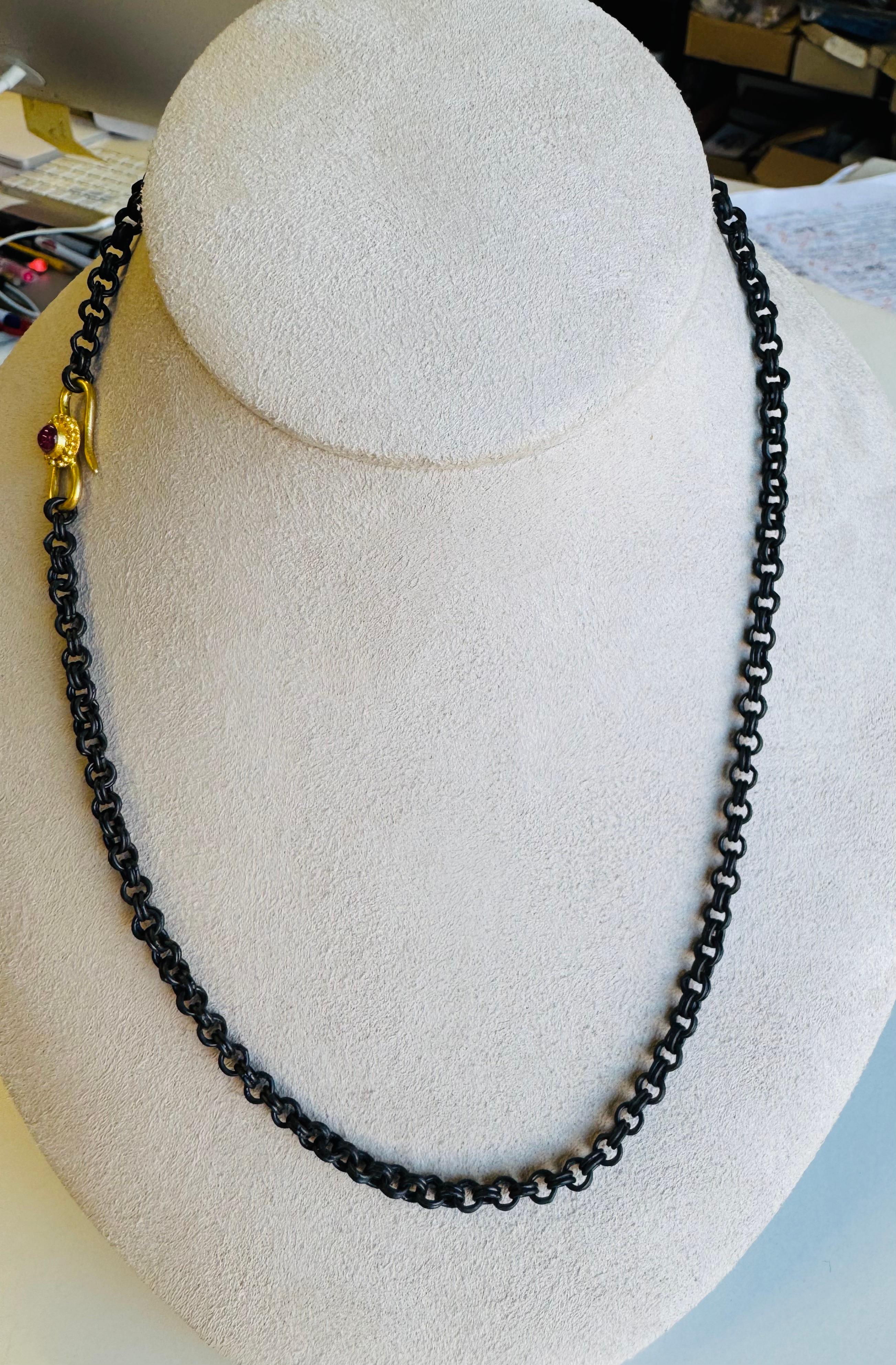 This oxidized copper chain offers a striking contrast to its clasp—a classical ruby cabochon set in rich 22 karat gold and adorned with delicate granulation. Rugged yet refined, the piece blends earthy patina with timeless elegance.
The ancient