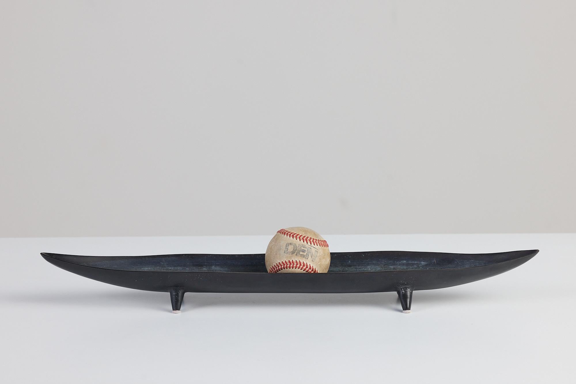 A black oxidized metal footed bowl. This bowl features a rectangular shape with pointed edges resembling a canoe or baguette. It would be a gorgeous decorative piece or serveware.

Dimensions: 21.75