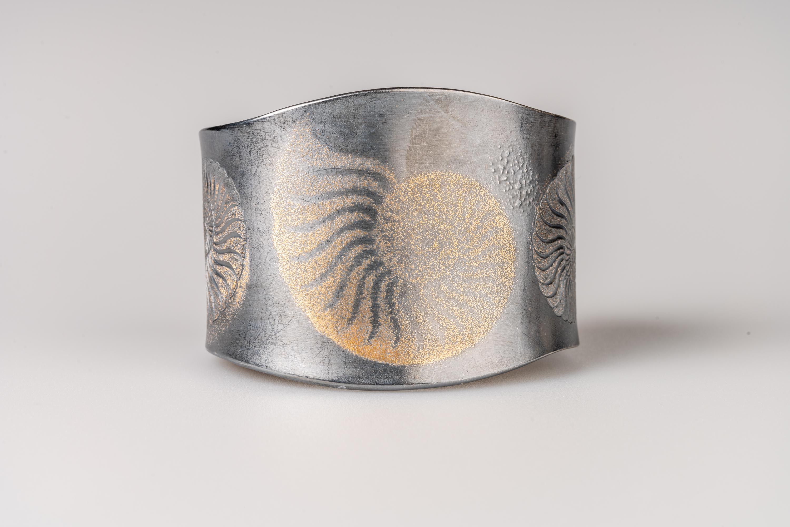 An oxidized sterling silver cuff featuring 24k yellow gold fairy dust in an ammonite design with hand engraved ammonites on the sides, measures 2.25inches x 1.73inches inside. This cuff was designed and made by llyn strong.