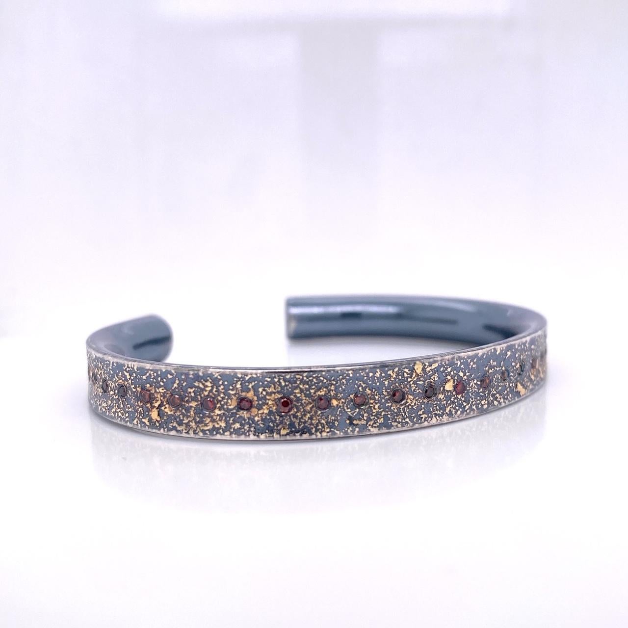 An oxidized sterling silver narrow cuff with 24k gold dust, set with 40, .256ct cabernet colored diamonds. This cuff was made and designed by llyn strong.