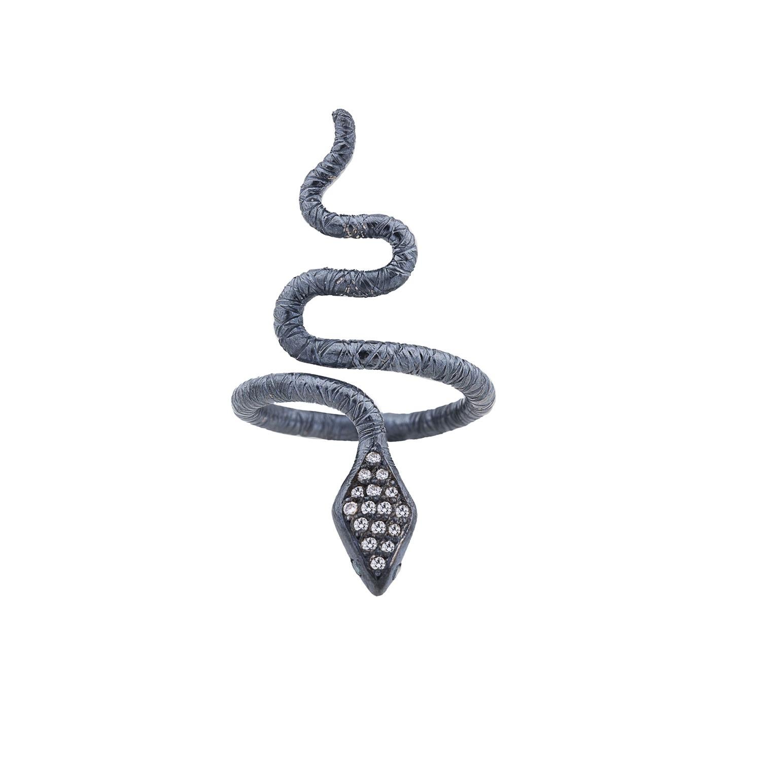 The Oxidized Sterling Silver Snake Ring by Lika Behar is a striking piece featuring a sinuous snake design intricately crafted from oxidized sterling silver. Adorned with sparkling white diamonds along its back and vivid green diamond eyes, this