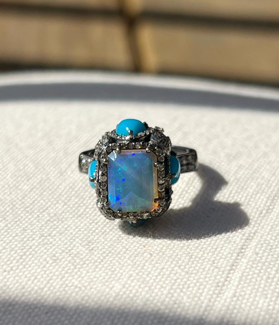 One oxidized sterling silver ring set with one pyramid faceted 10x8mm Ethiopian opal, one hundred eighty-two brilliant cut diamonds, approximately 1.00 carat total weight with matching I/J color and SI3 clarity, and four 7x5mm pear shaped cabochon