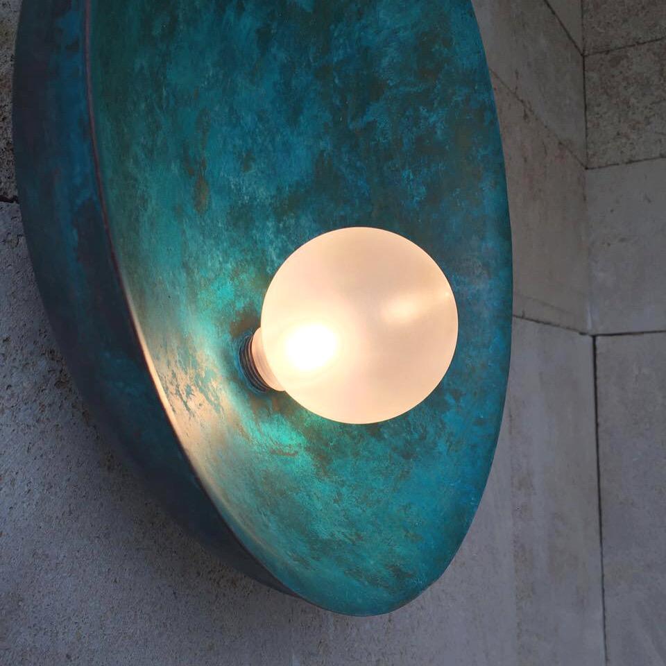Oyster brass turquoise sconce, Carla Baz
Dimensions: 110 x 40 x 18 cm
Materials: brushed brass, Vert-de-gris hand painted brass.

Oyster is a series of sculptural lighting pieces where the delicately nested pearl in its protective shell embodies