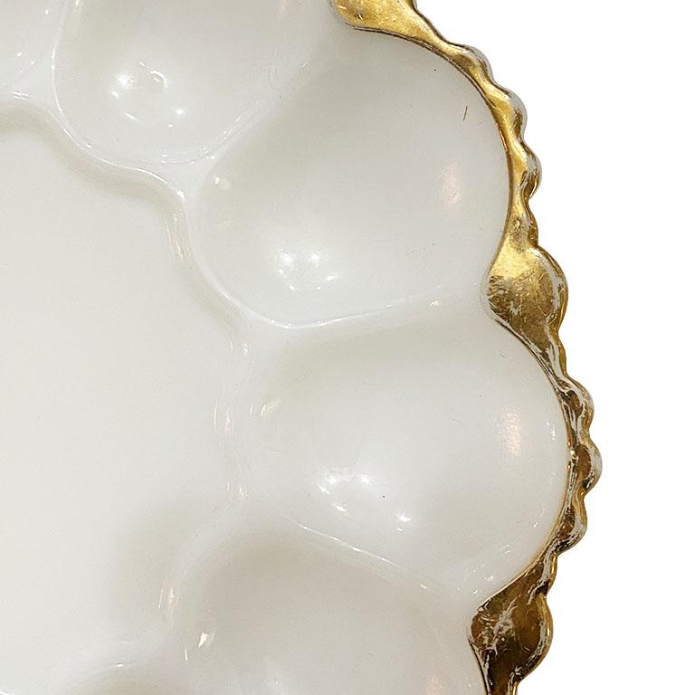 Bring a touch of elegance to any gathering with this milk glass platter. The scalloped edges are painted with a beautiful gold paint. The inside features wells for serving eggs, or oysters. The center is open and would be great to serve condiments.