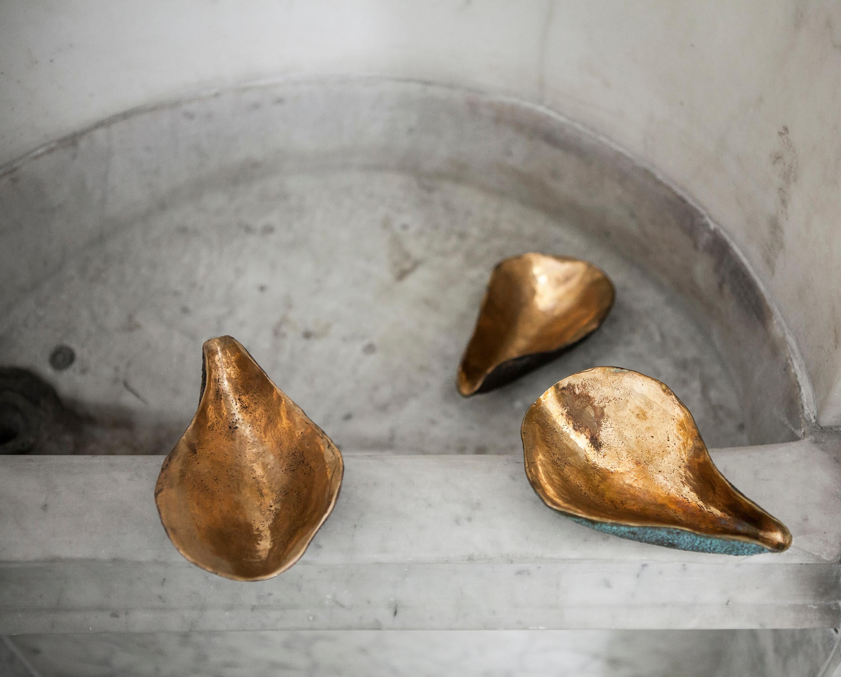 This solid bronze dish is an interior embellishment. 
The organic shape is sculpted by hand, richly textured on the outside and polished on the inside. Inspired by the feminine and evocative shapes of oyster shells, this home accessory will add a