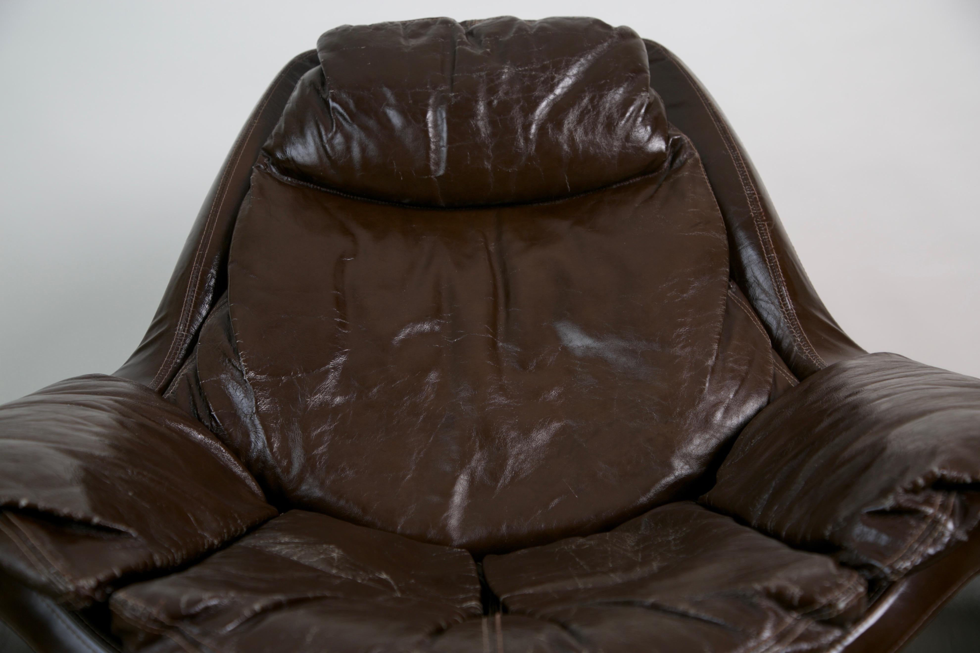 This model P-60 leather lounge chair and ottoman is part of the Proposals series, for Saporiti Italia, designed by Vittorio Introini in the 1960s. The glossy dark brown leather has the feel of patent leather which provides a swank, comfortable and