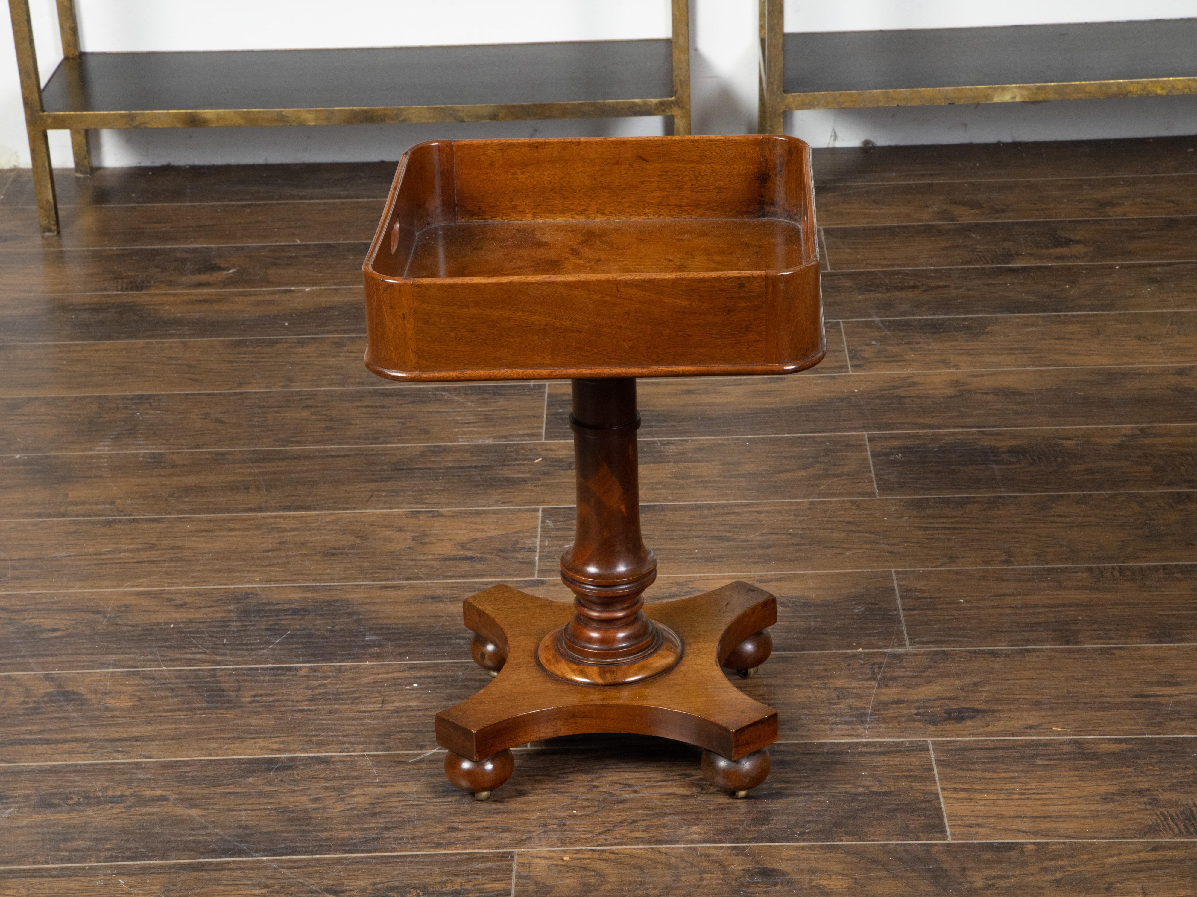 An English mahogany tray top table from the 19th century, with turned pedestal base and onion feet. Created in England during the 19th century, this mahogany table features a large tray top with lateral pierced handles, sitting above a turned