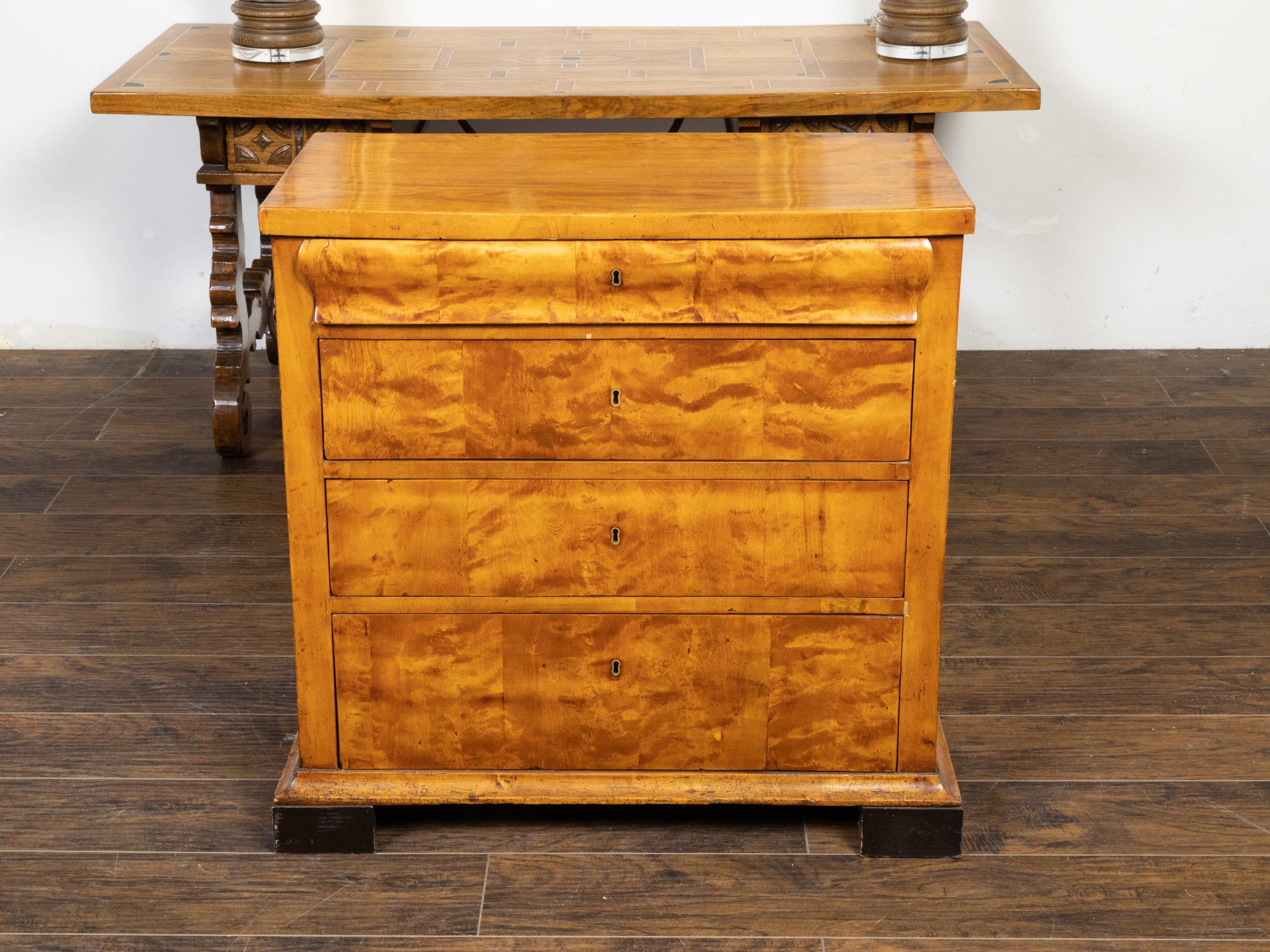 An Austrian Biedermeier period walnut veneered commode from the 19th century with four graduated drawers and rectangular ebonized block feet. Created in Austria during the 19th century, this Biedermeier commode features a rectangular top sitting