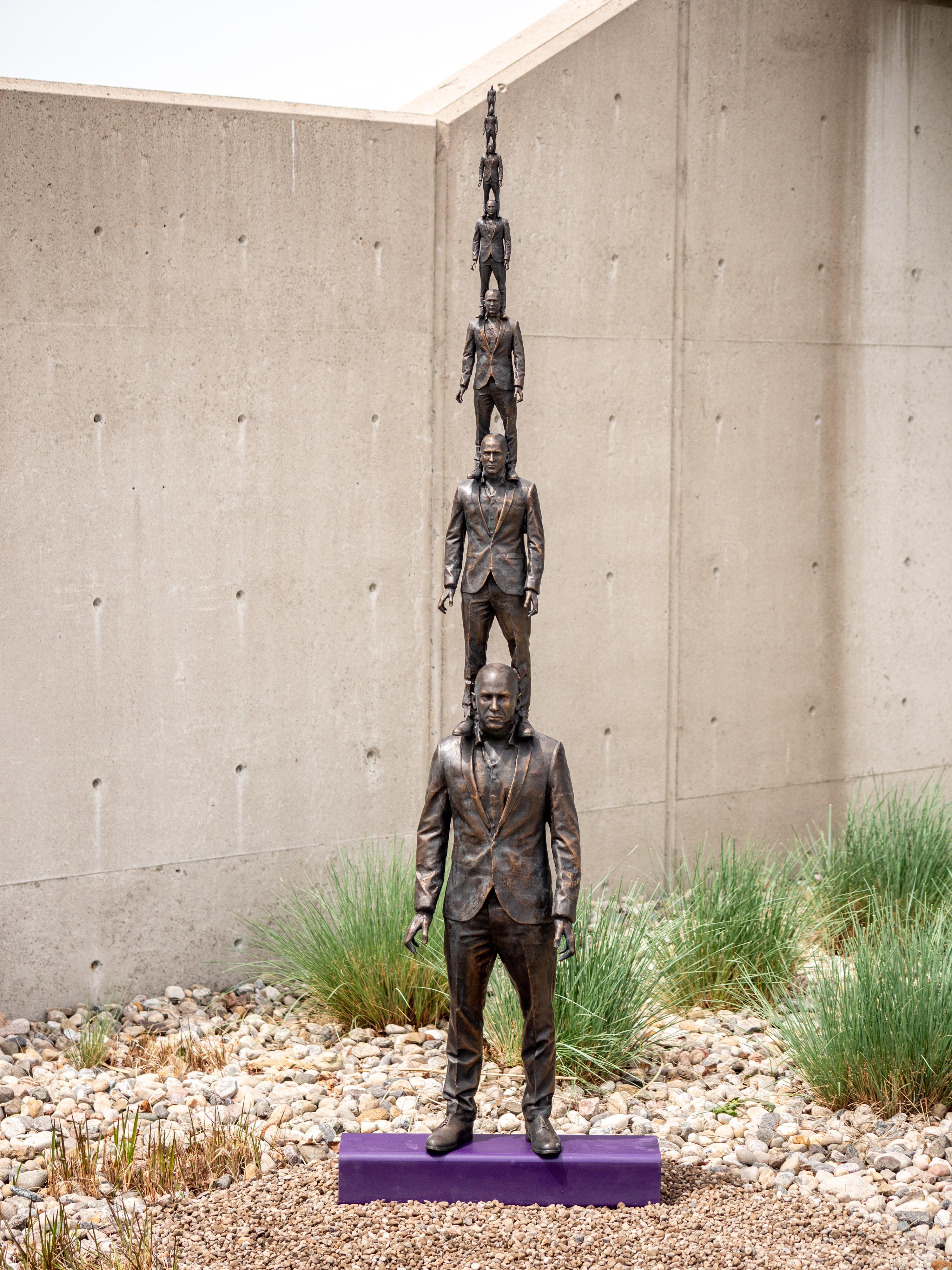 Evolution of a Vantage Point 1/4 - Seven bronze suited men in diminishing size