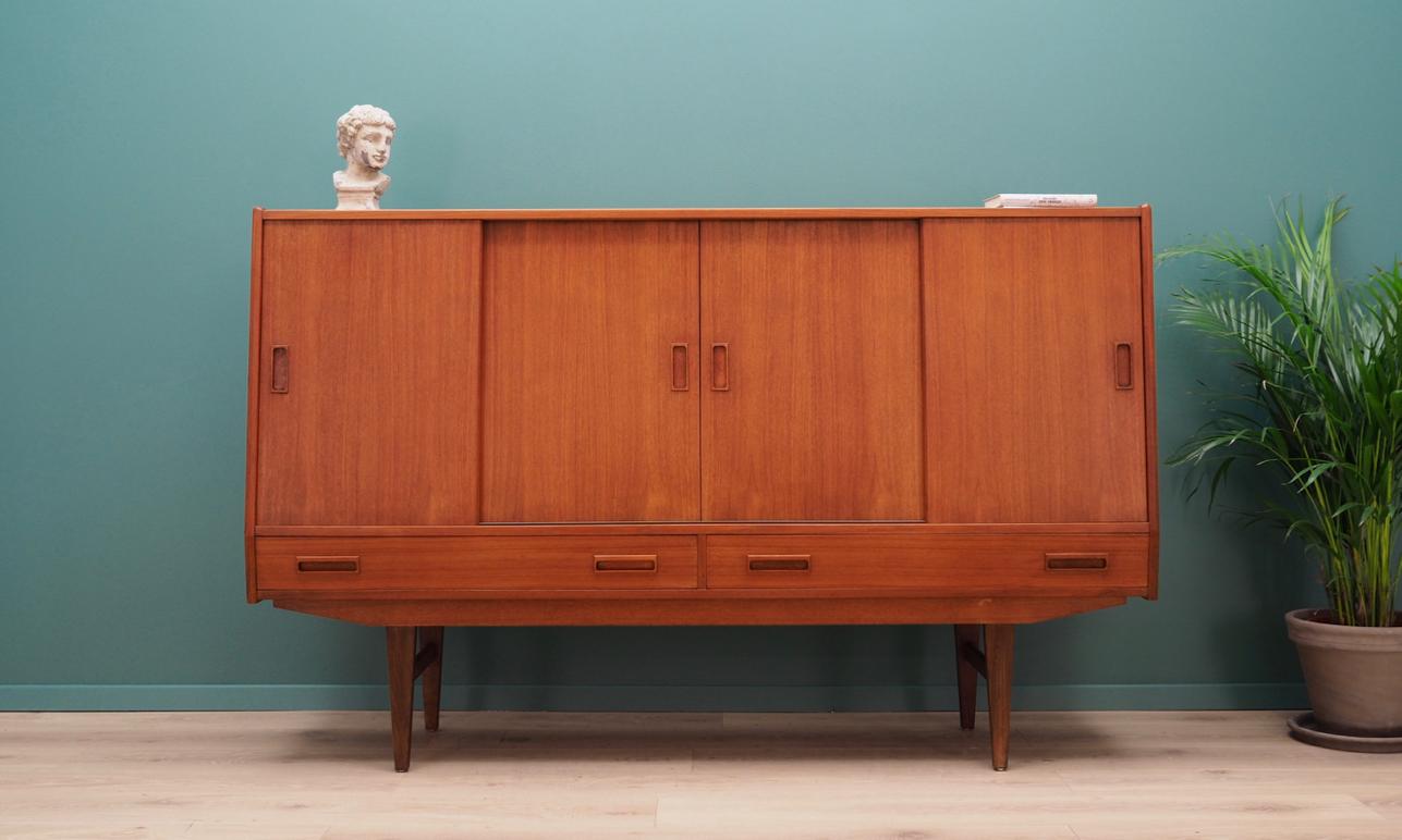 Brilliant highboard from the 1960s-1970s. Scandinavian design, Minimalist form. Manufactured by P.Westergaard Mobelfabrik. The surface of the furniture finished with teak veneer. Shelves with adjustable shelves and a decorative mirror behind a