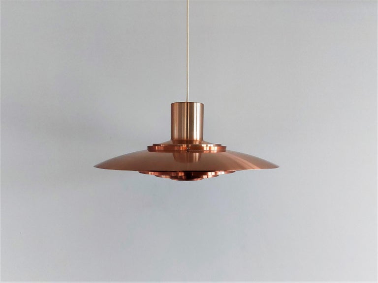 The gorgeous P376 pendant lamp was designed by Preben Fabricius and Jørgen Kastholm for Nordisk Solar in 1964. It has a large upper shade and four rings that are slightly curved towards the middle to cover the bulb. When this pendant is lit, it