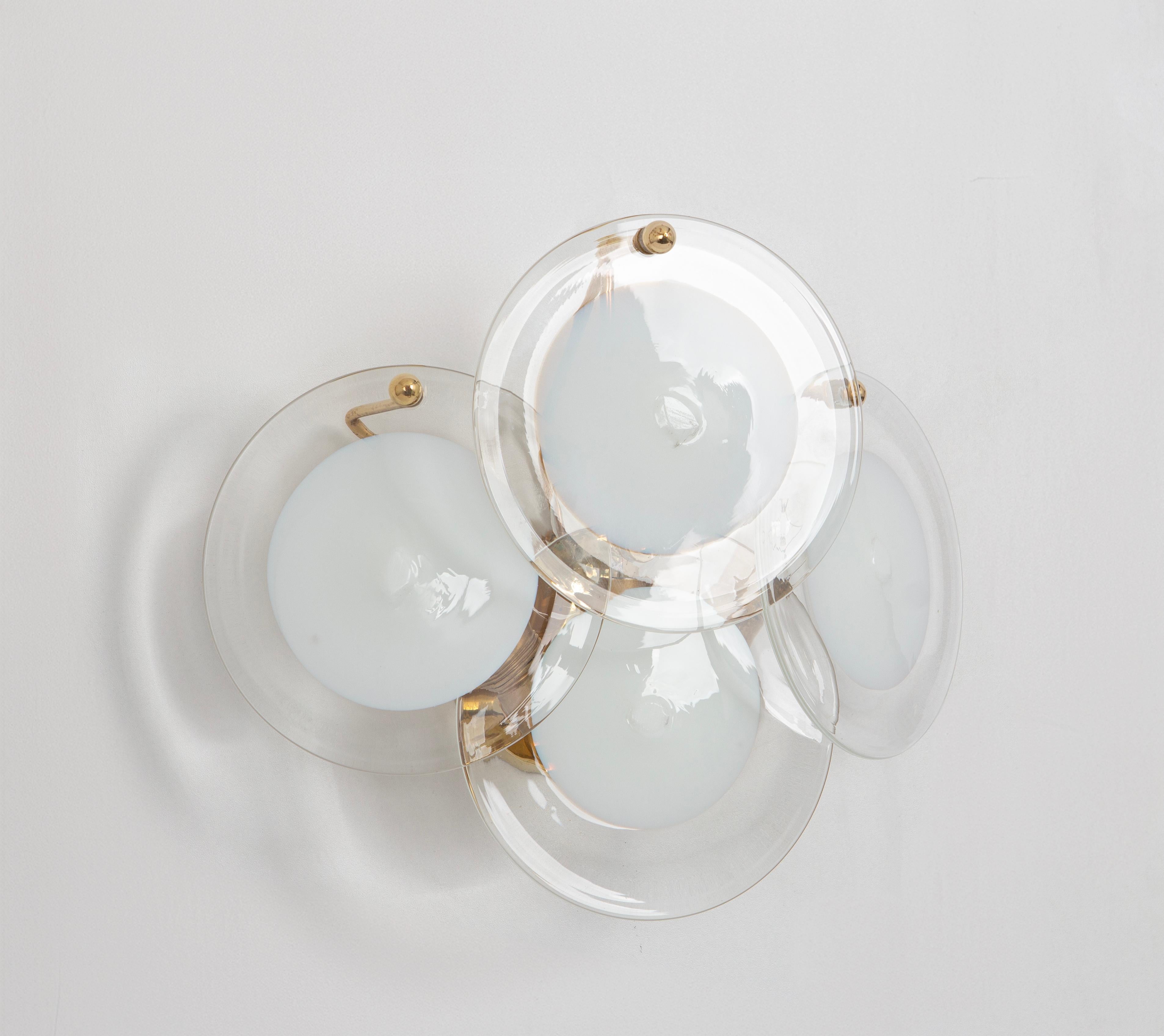 A stunning pair of wall light by Vistosi, Italy, manufactured in, circa 1960-1969
Four Murano disc glasses in each wall lights over a brass frame.
High quality and in very good condition. Cleaned, well-wired and ready to use. 
The fixture requires 2