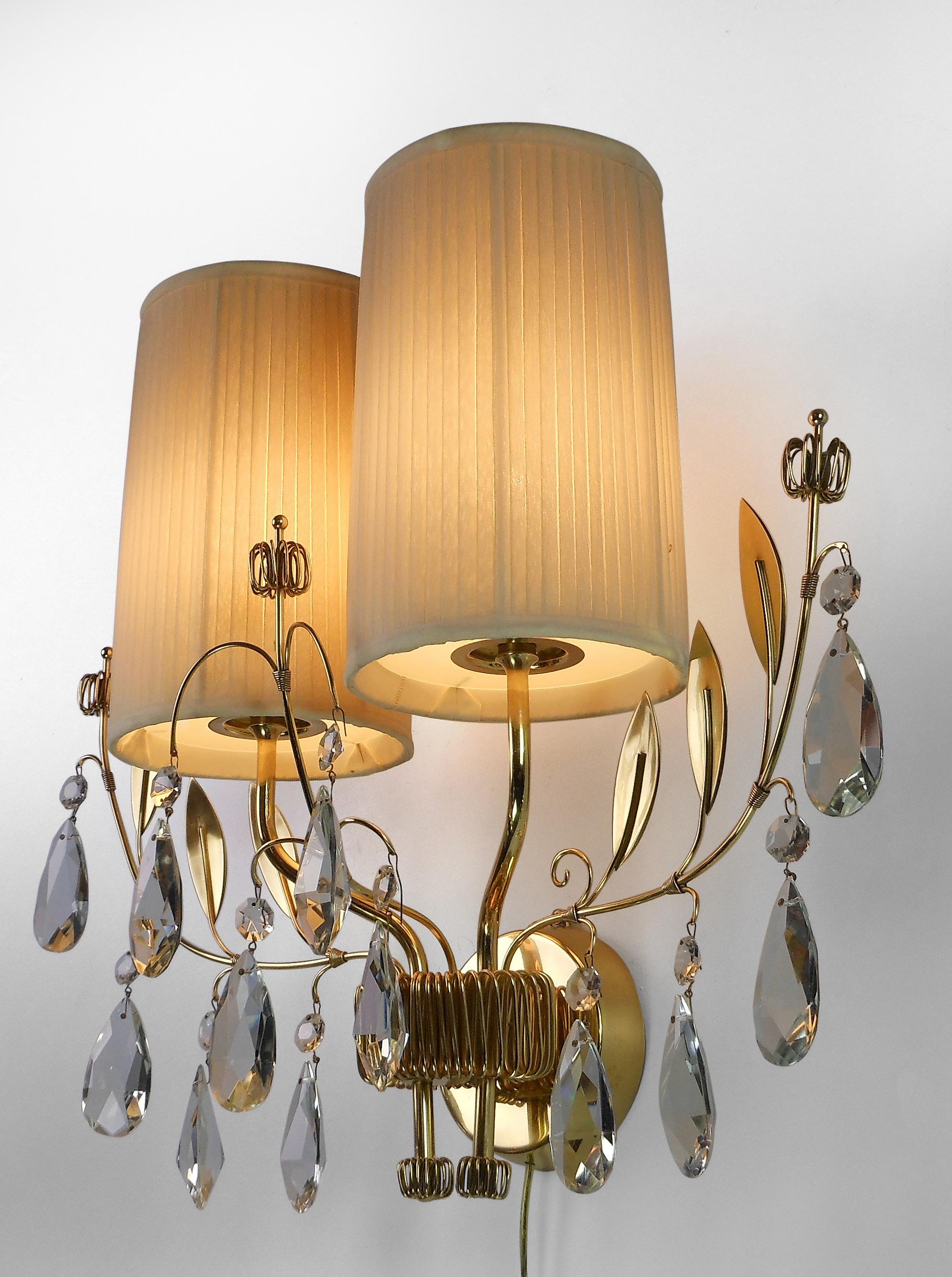 A single finnish crystal and brass sconces
Mid-20th century
This rare model possesses Tynell's distinctive leaves and flowers with sparkling crystal drops. Dignified and playful, a delightful sconce. The circular backplate issuing two s-form arms