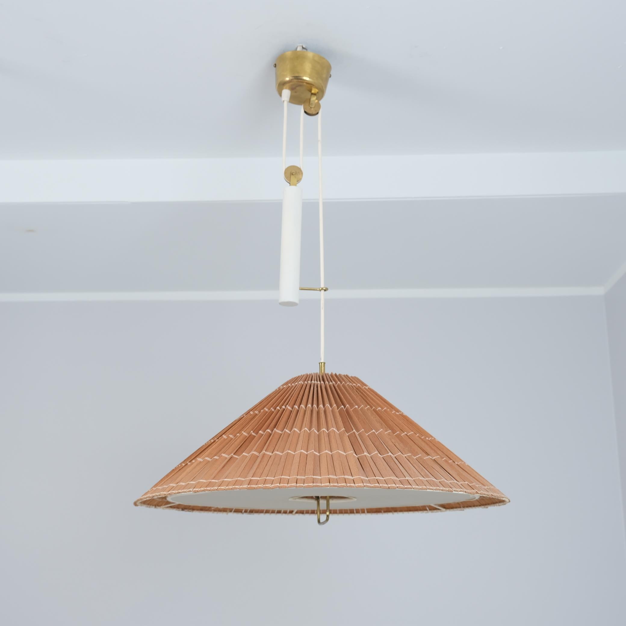 A beautiful adjustable lamp by Paavo Tynell that harmoniously combines many elements such as brass, wooden slats, plastic defuser, painted metal and the wirings.
The lamp has all original parts except for the renewed wooden slat shade that was