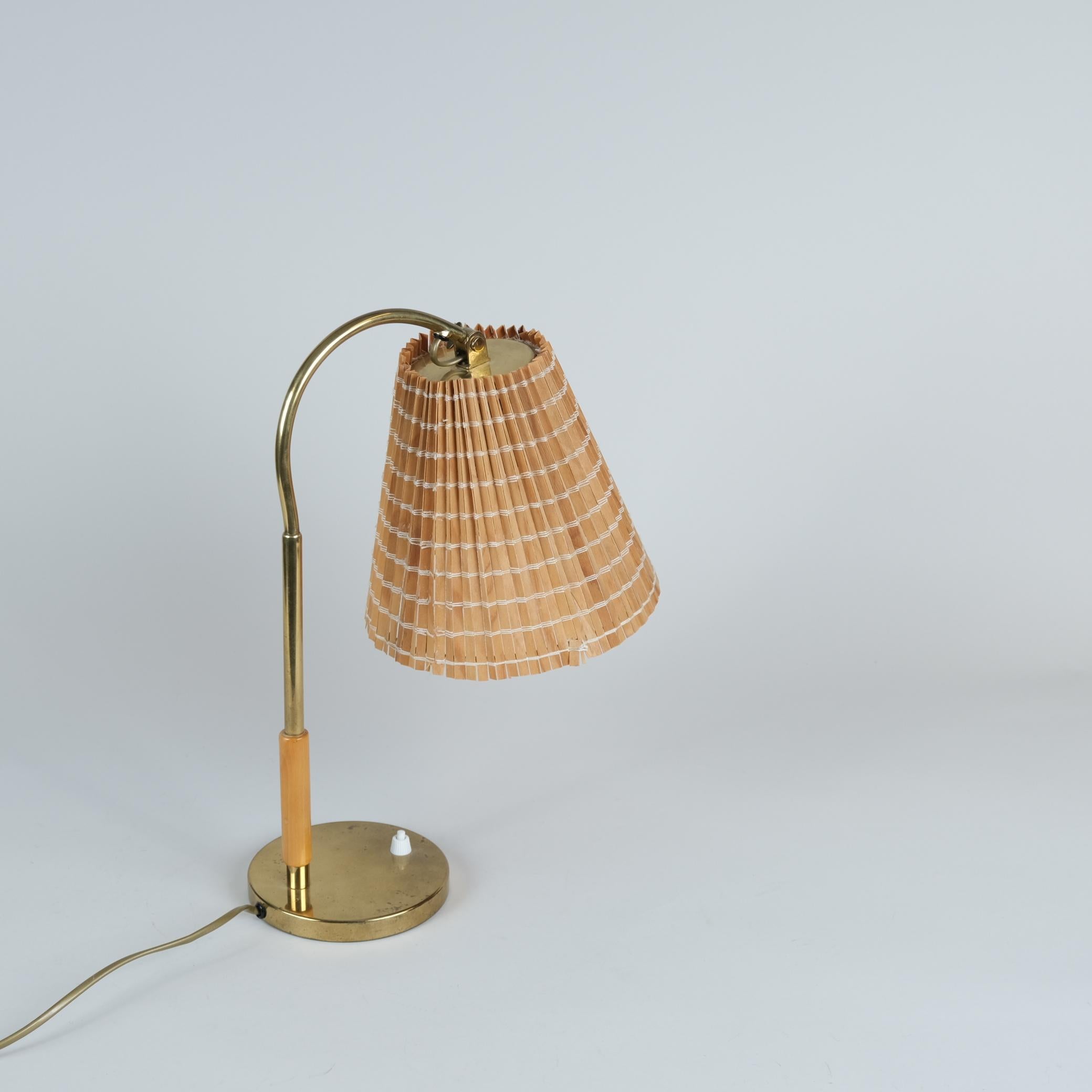 Un bonito ejemplo de la lámpara de mesa regulable modelo 9201 diseñada por Paavo Tynell en la década de 1940 para Taito Oy.
Esta delicada lámpara de mesa tiene un cuerpo de latón con una parte de mango de madera en la parte inferior del vástago. 
La
