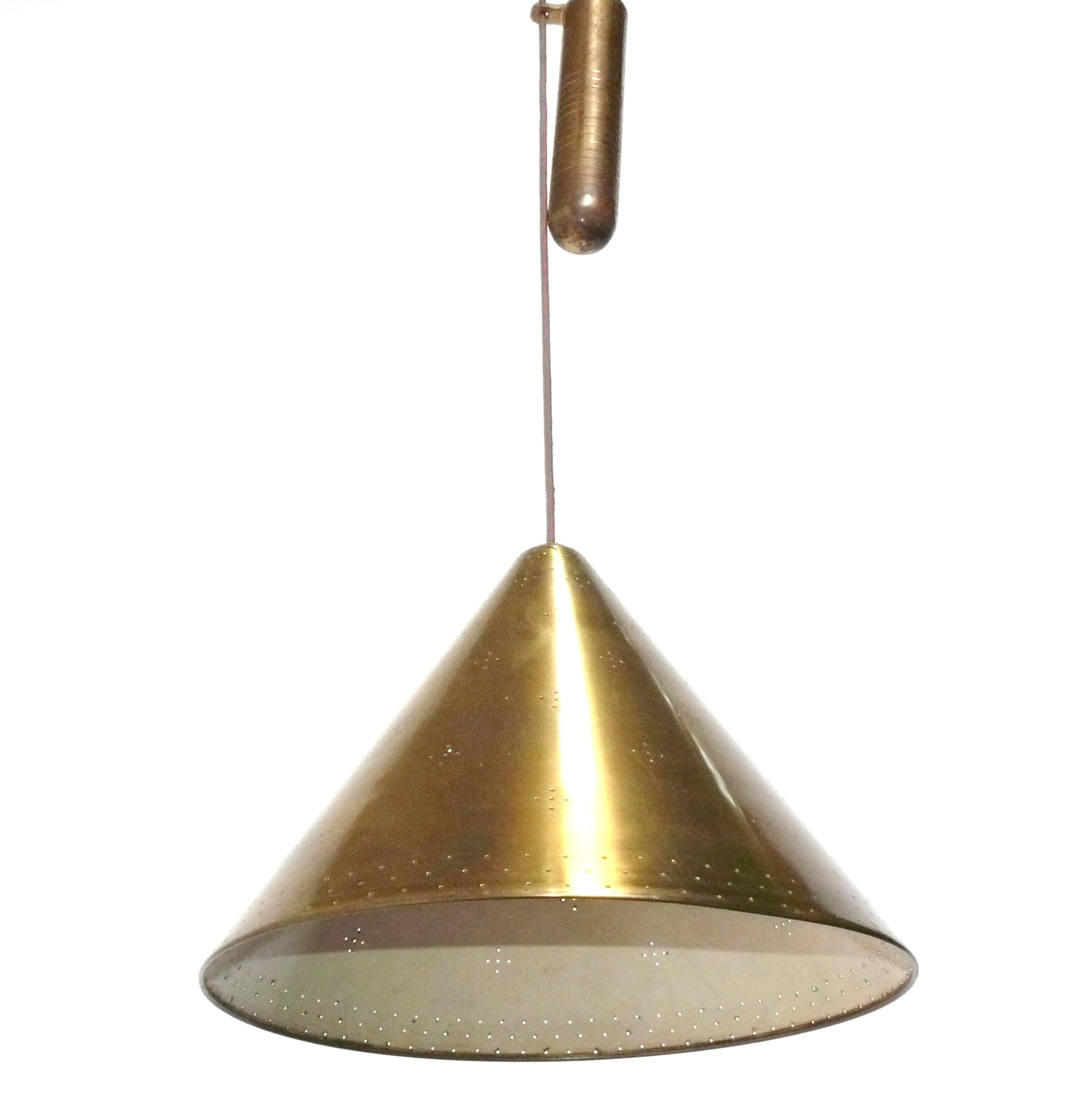 Lustre à contrepoids en laiton, attribué à Paavo Tynell, non signé, Finlande, vers les années 1950. Il a été recâblé et est prêt à être utilisé. Elle est fabriquée en laiton et en métal fini laiton, avec un abat-jour perforé qui émet une lumière
