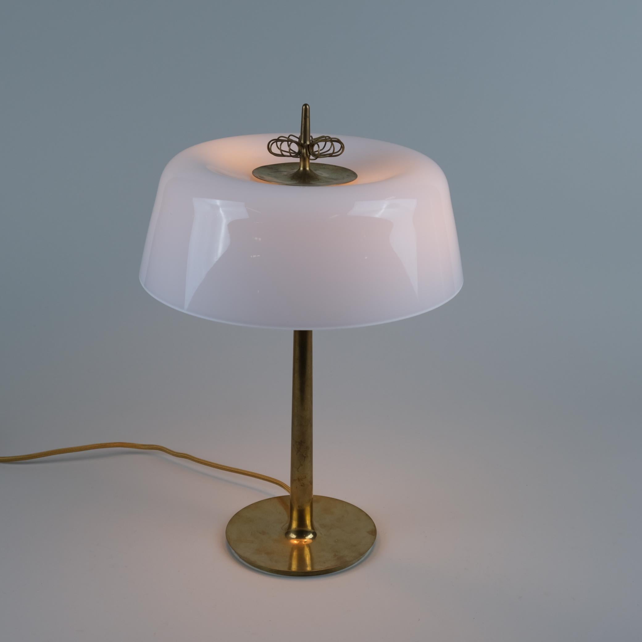 Une lampe de table élégante et rare, modèle 9211, conçue par Paavo Tynell et fabriquée par Taito en Finlande dans les années 1950. Le corps de la lampe est en laiton moulé et présente une forme élégante et sans couture recouverte d'un abat-jour en
