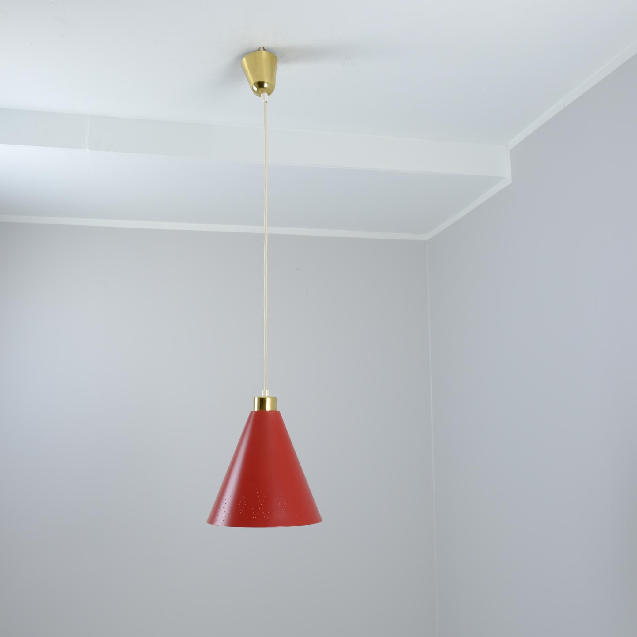 A lively Paavo Tynell pendant lamp crafted in brass and painted red metal, distinguished by the designer's iconic perforations. This model features a distinct fishtail and diamond perforation, nicknamed for its resemblance to a fish's tail and
