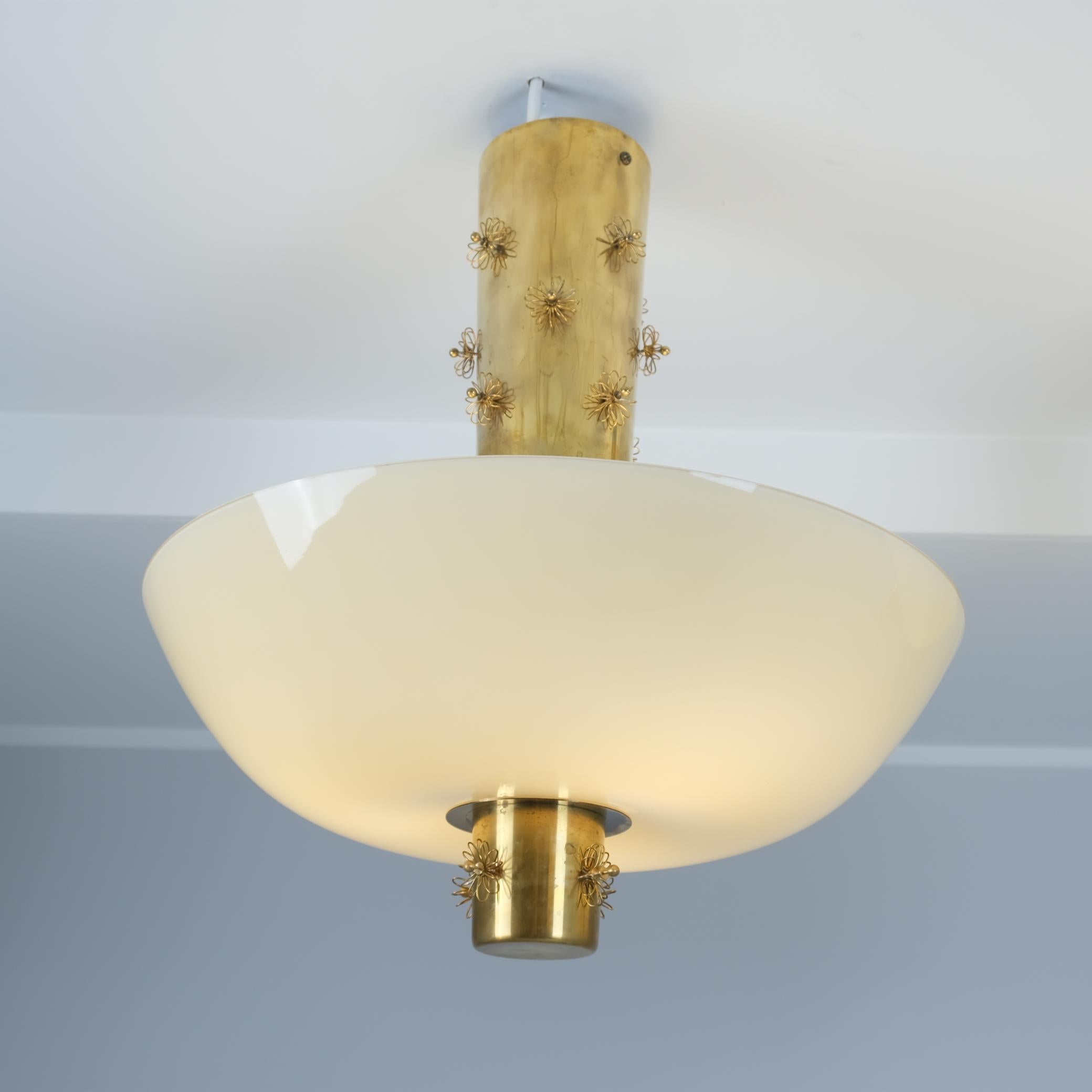 Dalla serie iconica di Paavo Tynell, soprannominata la conchiglia Cannon, questo bellissimo pezzo ha l'aspetto di una bomba che cade, ma anche la morbidezza della primavera grazie alle decorazioni floreali magistralmente posizionate sul fusto.  Il