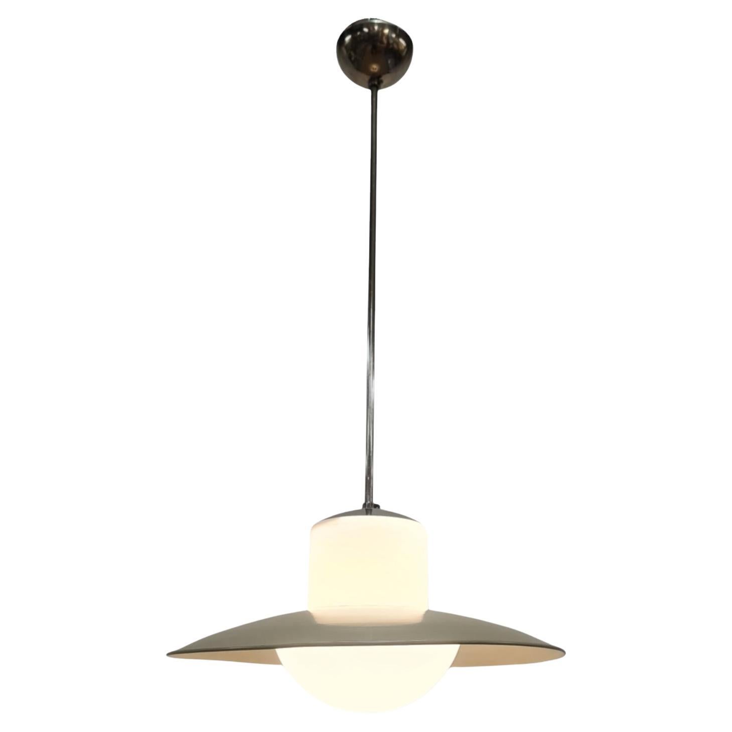 A Minimalist Mid-Century Modern lamp by Paavo Tynell produced by Idman in the 1950s. The lamp features a chromed body with a bell-shaped opaline glass shade topped by a greysh green metal shade. The lamp was designed already in the 1930s and has