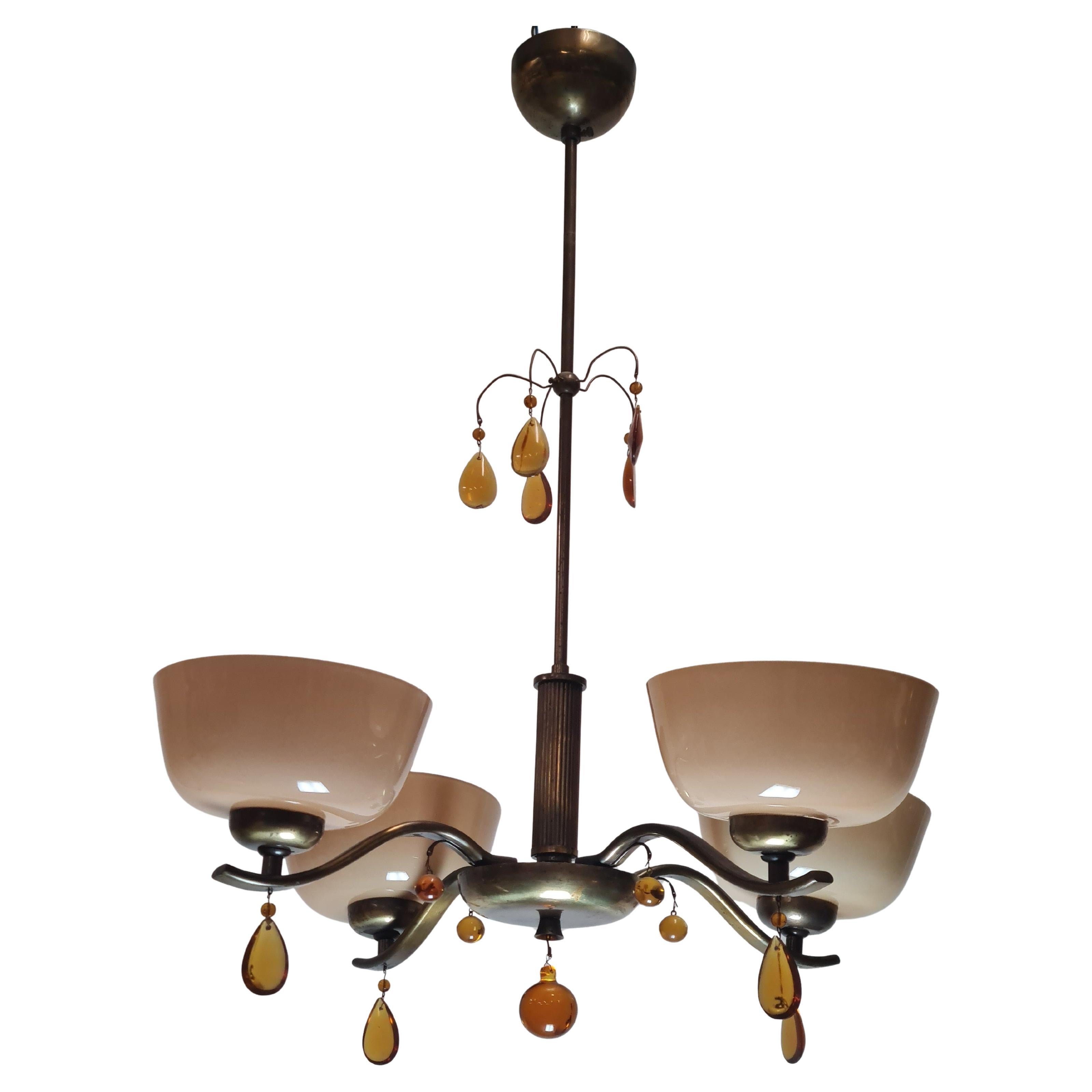 Uno squisito esempio di lampade di Paavo Tynell del 1930. Un pezzo meraviglioso con sfumature in vetro soffiato color champagne scuro (marrone chiaro) e corpo in ottone ossidato con cristalli a goccia color ambra. Il modello della lampada è 1464 e