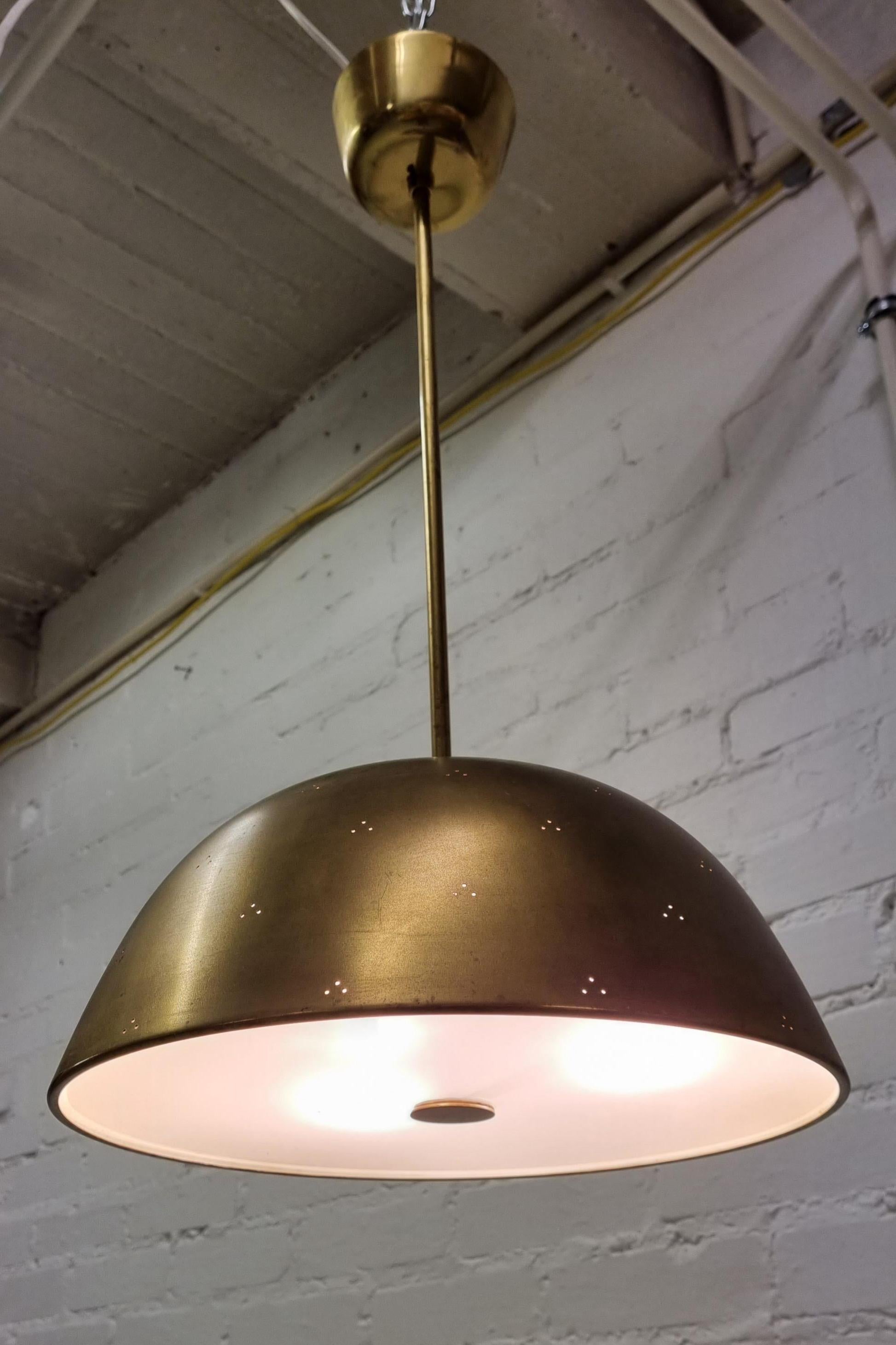 Very rare ceiling lamp model 1953 in its original condition by Finnish designer Paavo Tynell (1890–1973) for Taito.
The brass shade is perforated and the diffuser underneath is made of glass. Three light sources.
The overall impression of this