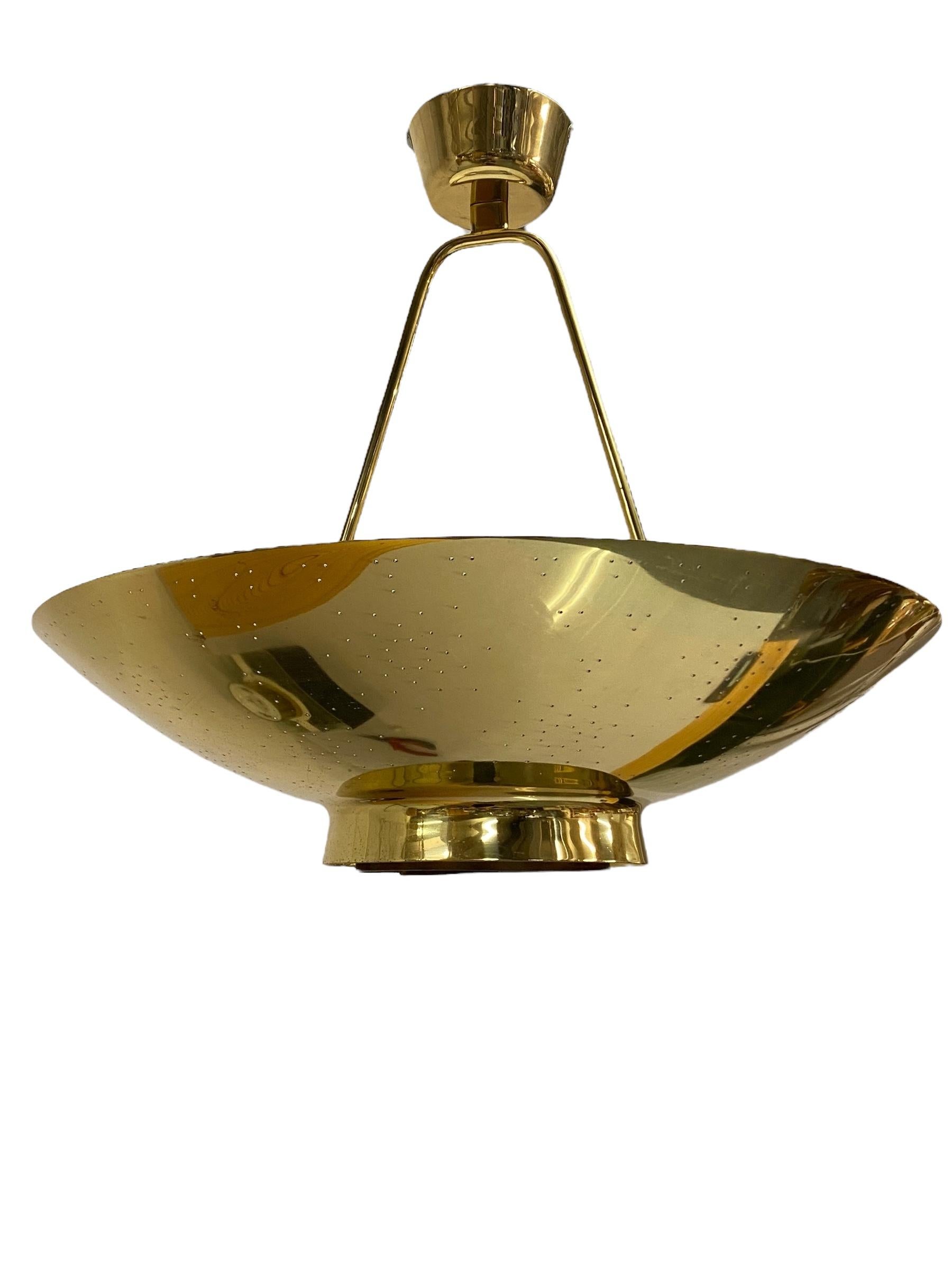 Lampada da soffitto Paavo Tynell modello 9060, alias la lampada UN prodotta da Idman in Finlandia negli anni Cinquanta. La lampada ha un design brillante con lamelle circolari centrali che riprendono il logo dell'ONU e sono abbracciate dal