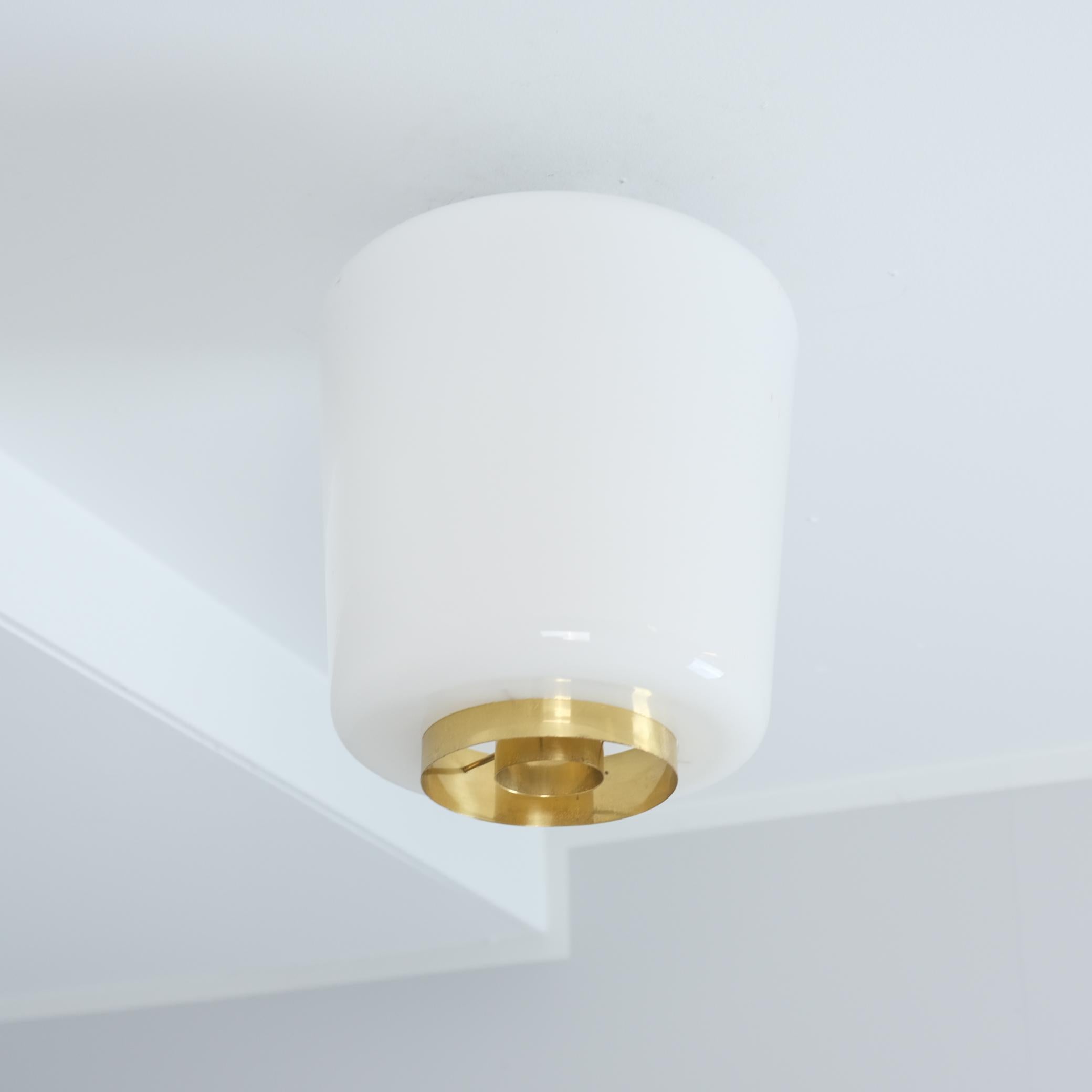 Una piantana minimalista di metà secolo moderno di Paavo Tynell in vetro opalino e dettagli in ottone. Un design molto semplice che aggiunge un tocco di modernità a qualsiasi interno. Perfetto per corridoi, piccoli spazi, ingressi, bagni e cucine.