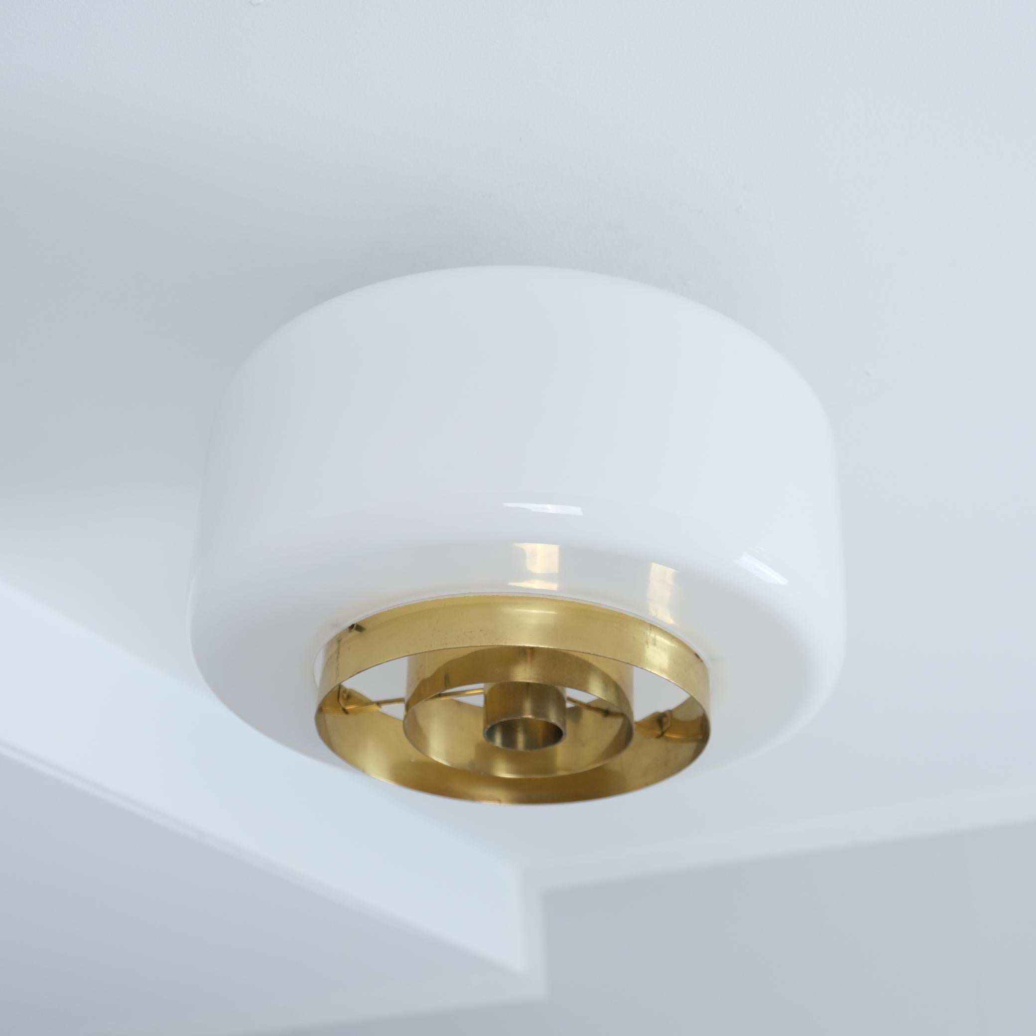 Una piantana minimalista di metà secolo moderno di Paavo Tynell in vetro opalino e dettagli in ottone. Un design molto semplice che aggiunge un tocco di modernità a qualsiasi interno. Perfetto per corridoi, piccoli spazi, ingressi, bagni e cucine.