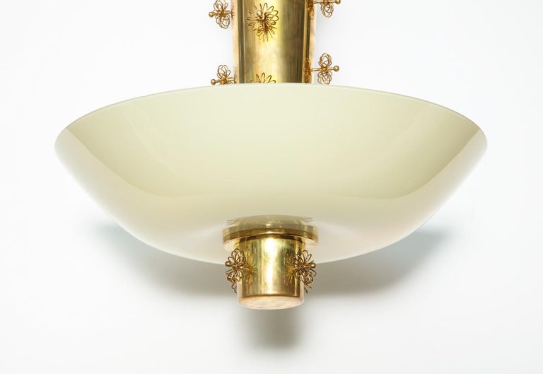 Rare hanging light by Paavo Tynell (1890-1973). Model #9040, manufactured by Taito Oy, Helsinki, Finland. Polished brass cone standard with applied brass-wire flowers. Original opaque, off-white, blown-glass bowl-shaped shade, conceals 3 standard