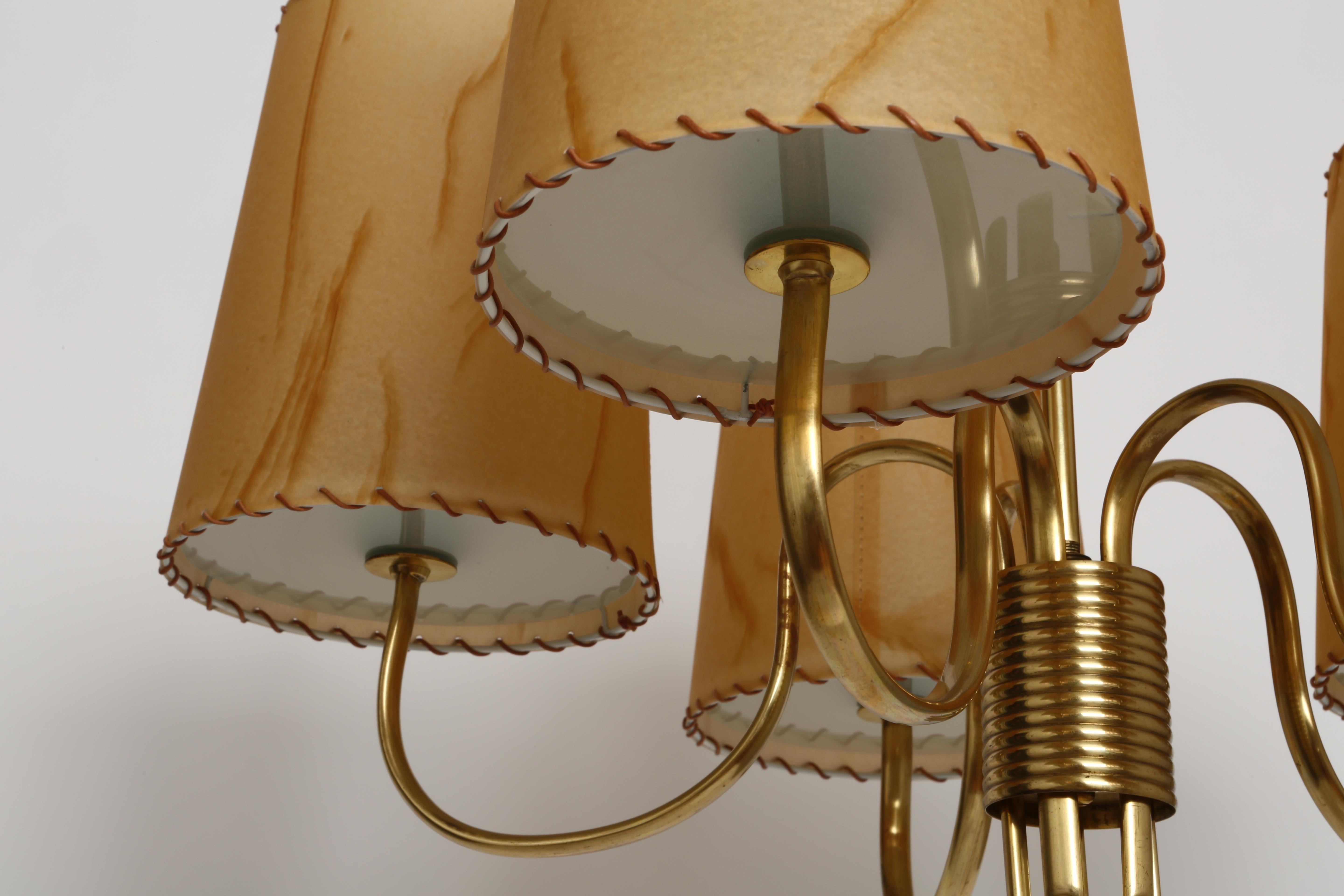 Paavo Tynell five-arm chandelier.
Finland, 1960s.
Brass leaf decorations.
Parchment paper shades with glass diffusers.
 