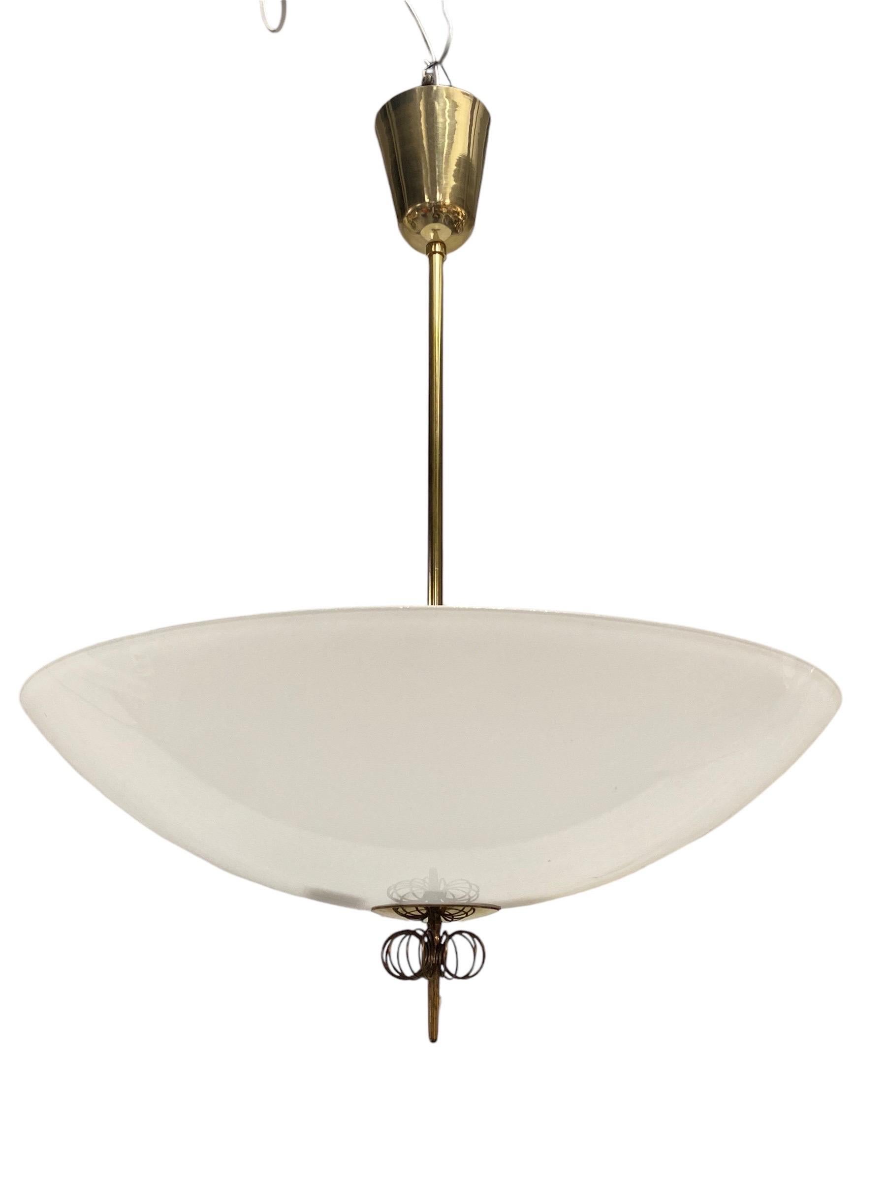 Magnifique plafonnier The Scandinavian Modern Modern en laiton et verre, conçu par Paavo Tynell et fabriqué par Idman en Finlande dans les années 1950. La lampe présente un grand abat-jour en verre associé à une tige en laiton et à une décoration en