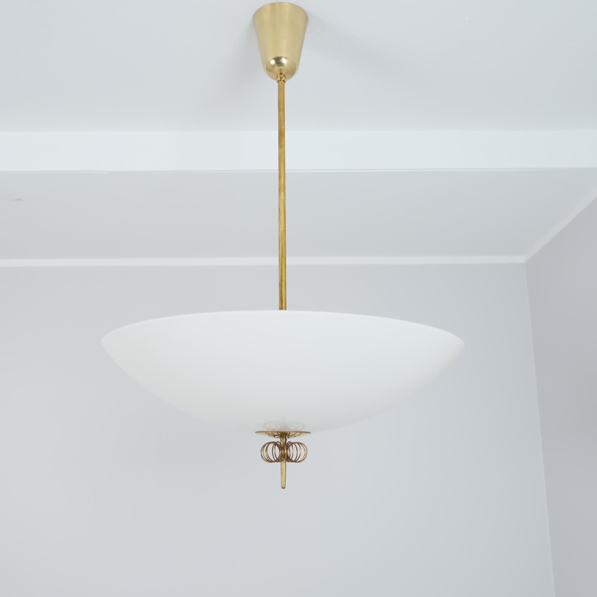 Magnifique plafonnier The Scandinavian Modern Modern en laiton et verre, conçu par Paavo Tynell et fabriqué par Idman en Finlande dans les années 1950. La lampe présente un grand abat-jour en verre associé à une tige en laiton et à une décoration en