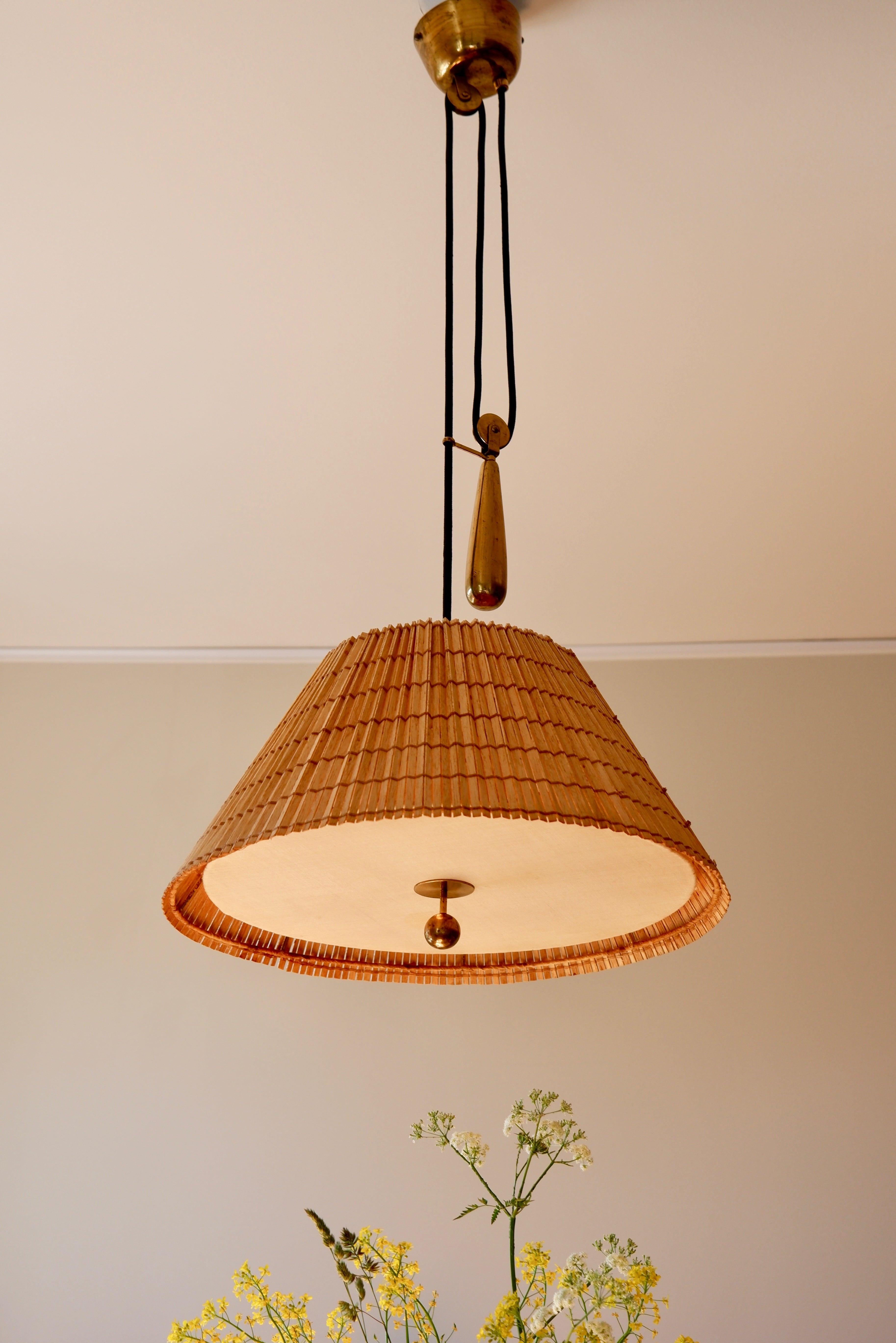 Counter Weight ceiling light model 1968 designed by Paavo Tynell and produced by TAITO OY in the 40's. The lamp is composed of a counterweight mechanism that goes up and down. The rattan shade has been restaured. Underneath you'll find a brass