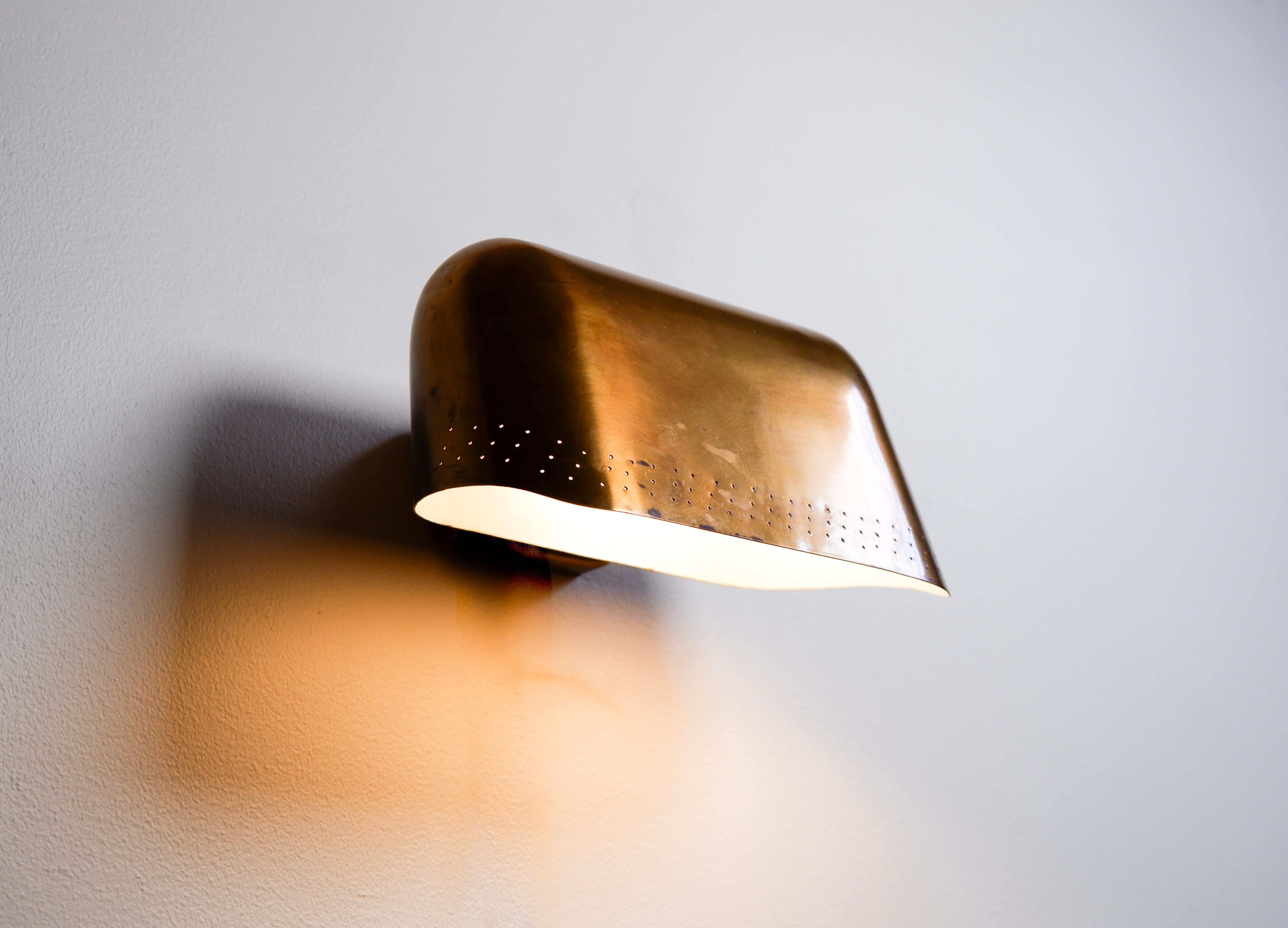 Extremly rare custom made wall lamp design by Paavo Tynell and made in solid brass with pierces holes. Drawing by the artist available on demand. the wall lamp can be used upon a desk or a painting due to its large size for a wall light. Extremely