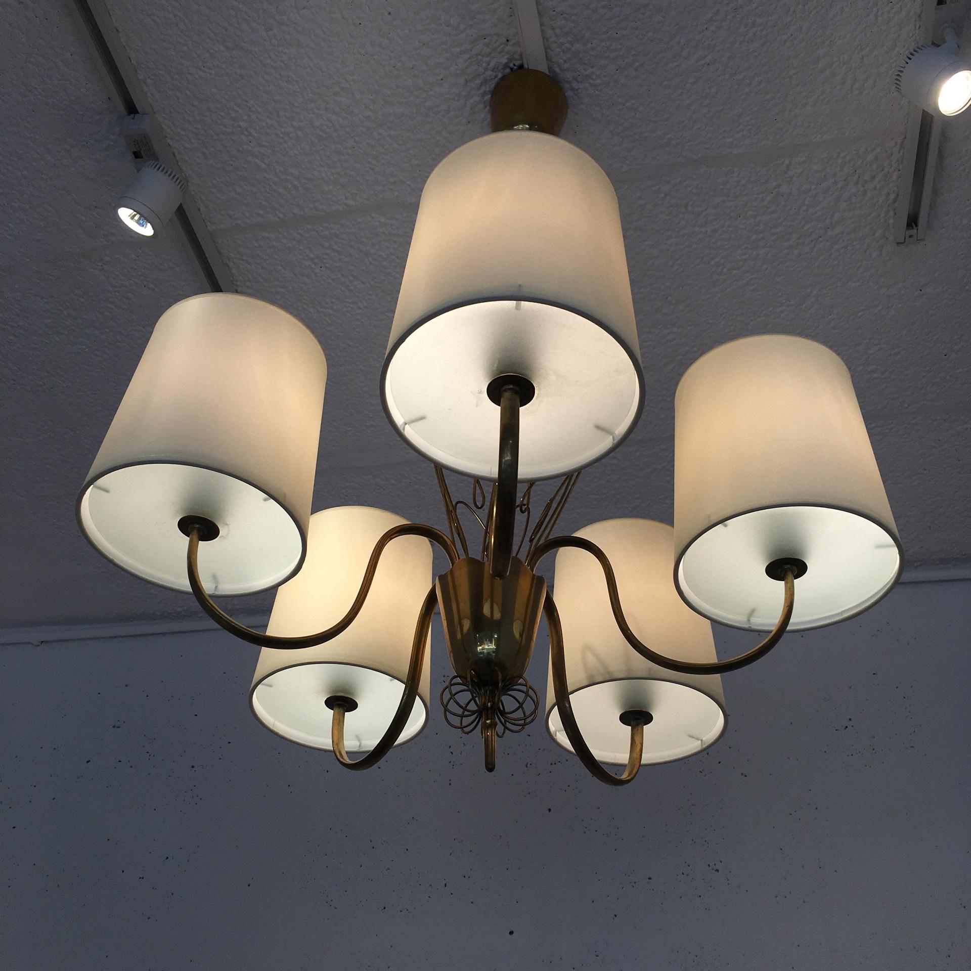 A Paavo Tynell model 9032 chandelier for Taito Oy, with five brass arms.
Each arm holds a parchment shade with glass bottom plates beneath.
The lamp is marked by Taito inside.