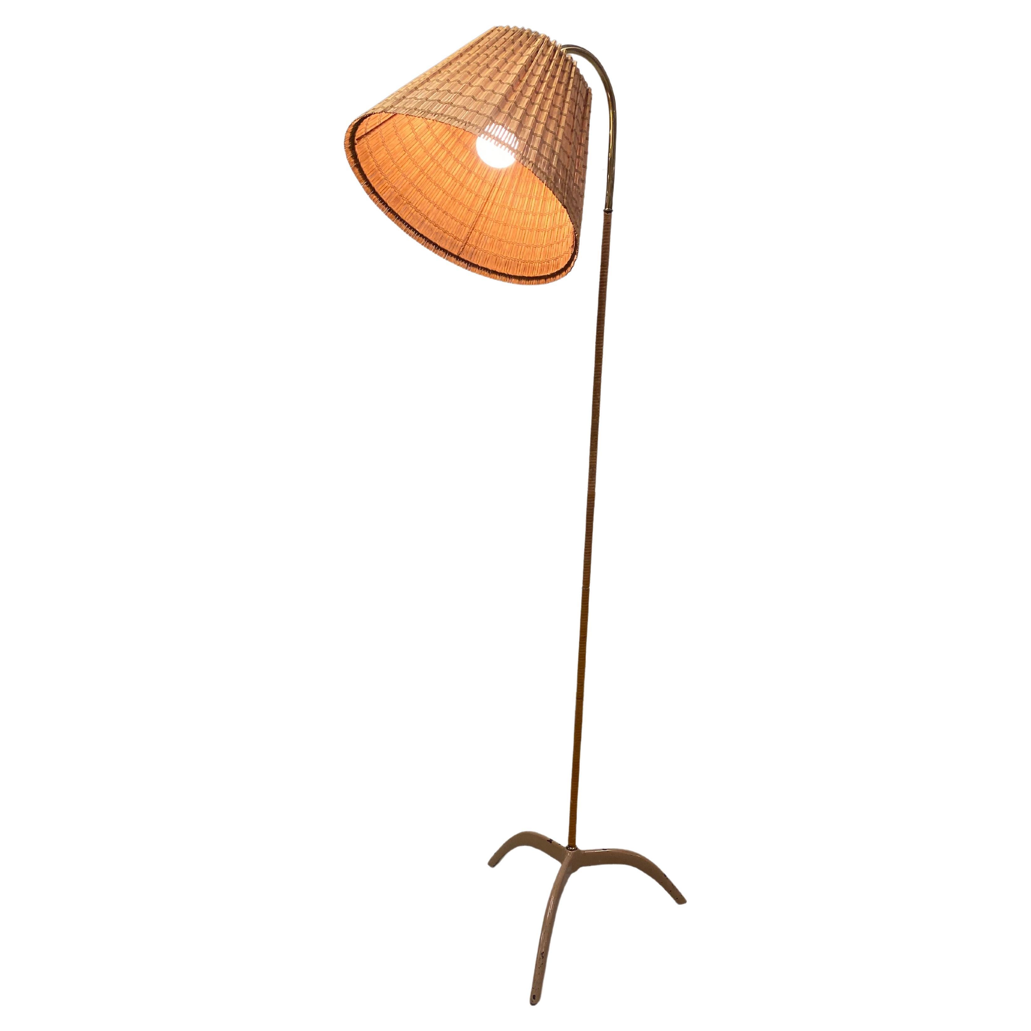 Paavo Tynell (1890-1973) original floor lamp model. 9609, manufactured by Taito Oy in the 1950s.  A beautiful floor lamp with a lacquered metal and rattan stem. All original parts excluding the beautiful renewed rattan shade. The bottom part (often