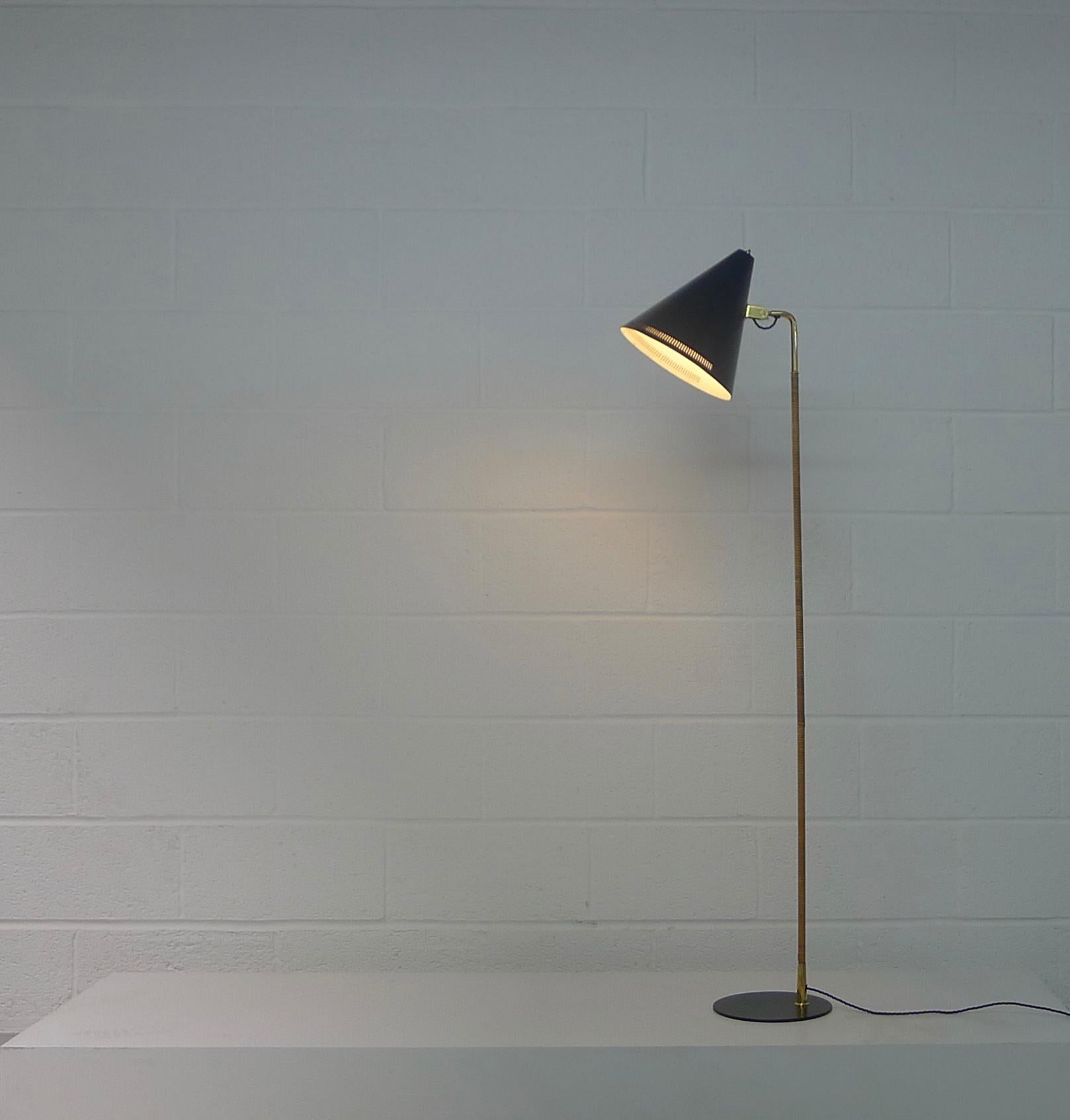 Paavo Tynell for Taito Oy, Finland, circa 1957. Floor lamp model K10-10 with black lacquered shade and base, brass stem with cane wrapping. Adjustable shade.

This is an early example produced by Taito Oy, after Idman took over production the base
